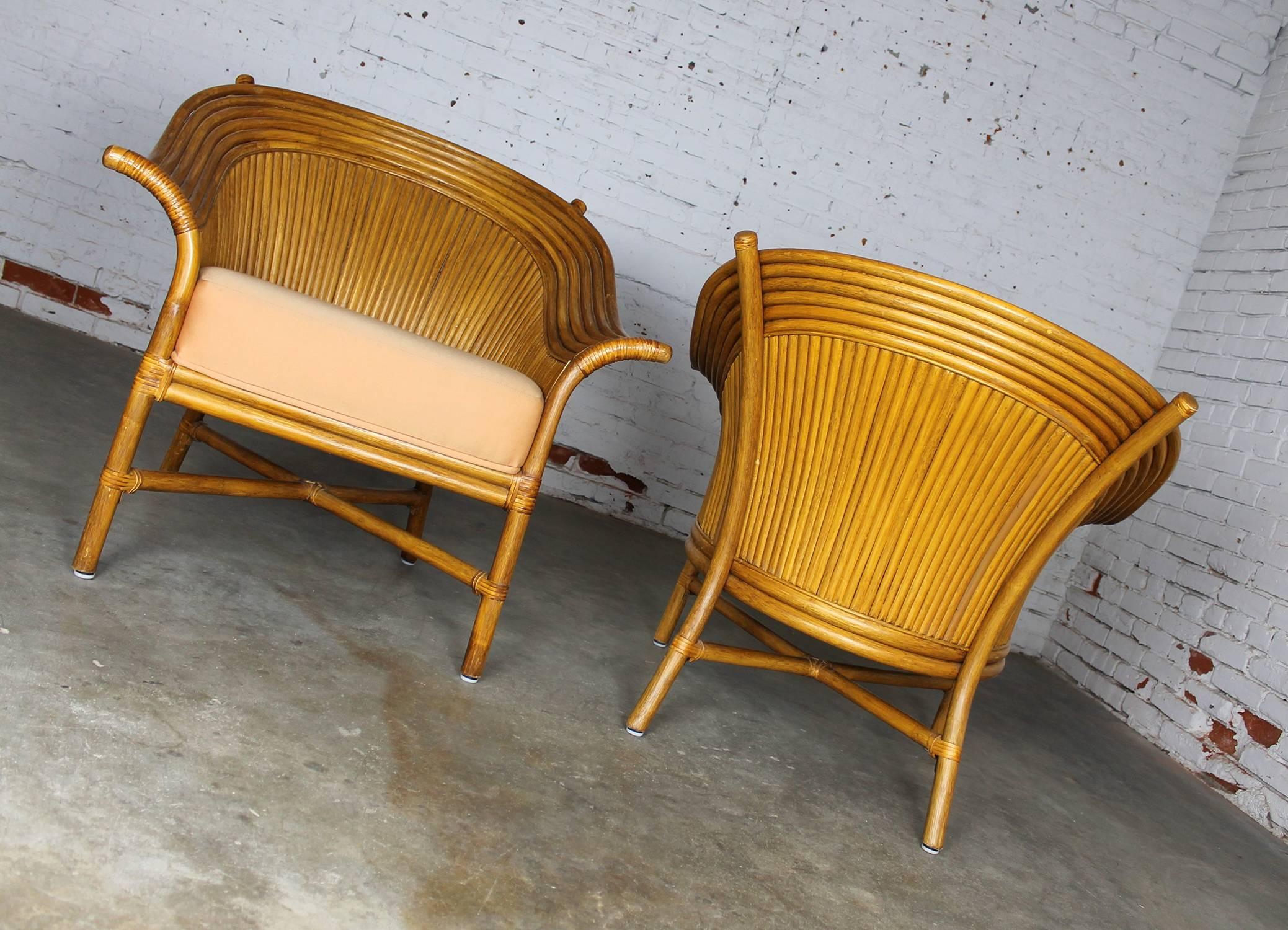 Awesome pair of circa 1990 fan back rattan club chairs in the style of McGuire. They have leather wrapped details, with a rather peach to Persian orange upholstered seat, and in wonderful vintage condition they are ready to use.

I can just see