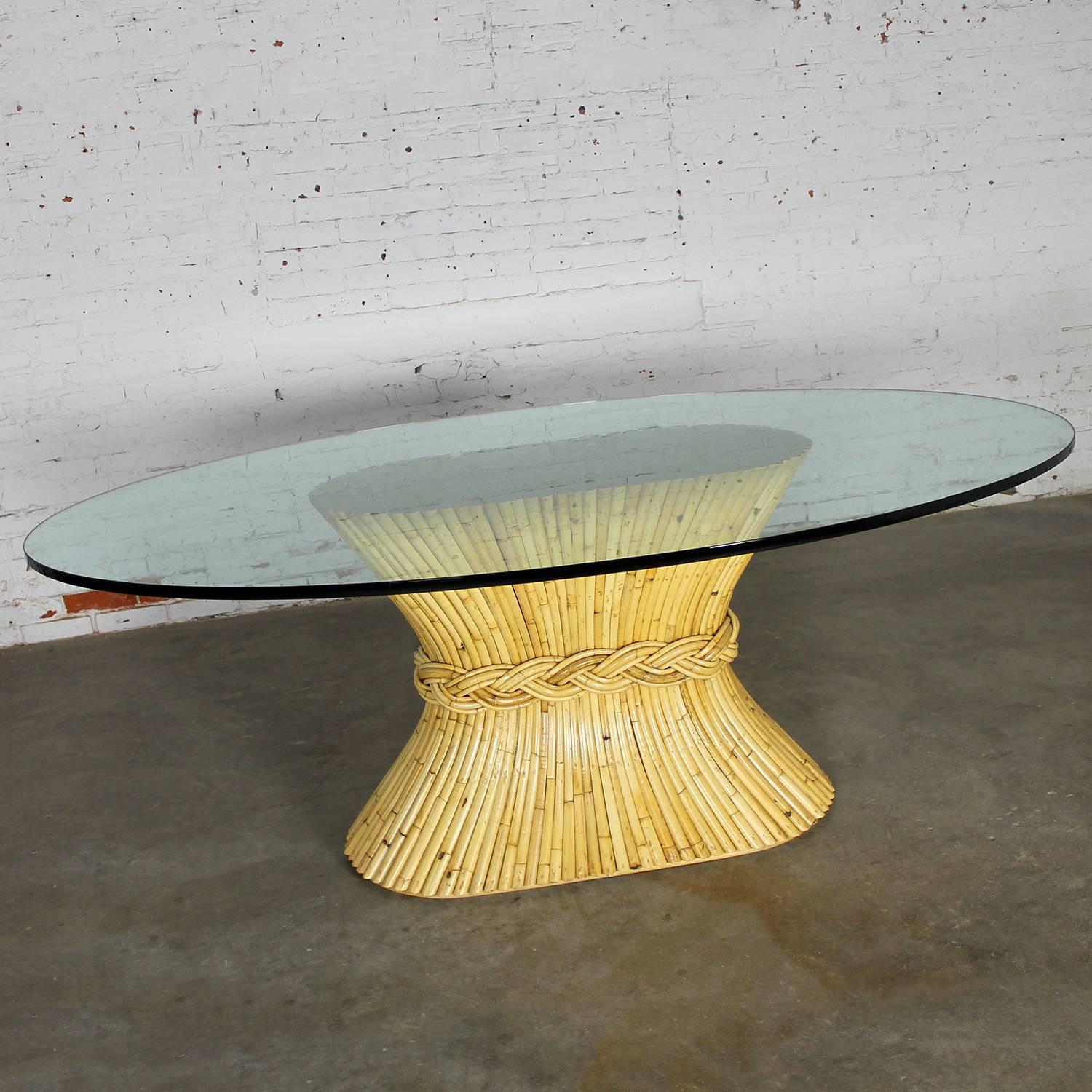 Vintage oval sheaf-of-wheat style rattan dining table by McGuire Furniture. Table is in wonderful vintage condition with normal wear and tear. The glass top does have one chip and may have some small scratches which come with age. We will sell and