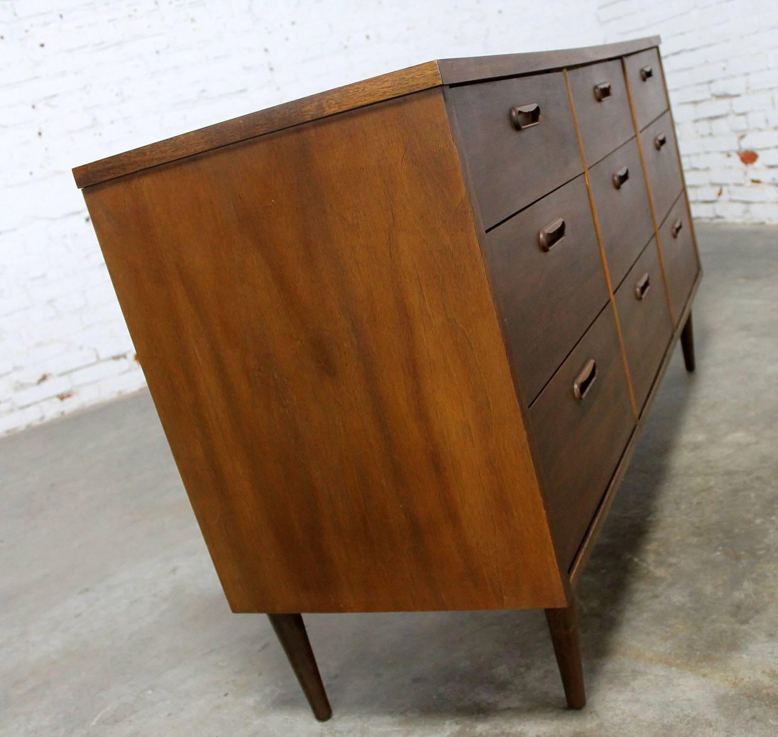 Handsome Mid-Century Modern walnut dresser with nine drawers in Danish or Scandinavian Modern style. This piece is in good original vintage condition, circa 1960. There are the normal nicks and dings you would expect for a piece of its age.

Who