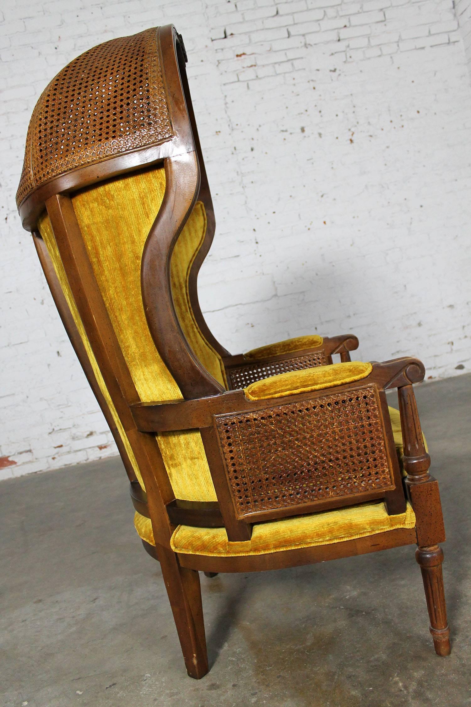 Vintage neoclassical style hooded cane porter’s chair in wonderful vintage condition. The original upholstery has no stains or tears and the caning in unharmed. There are small nicks and dings on the wood as you would expect with age but nothing