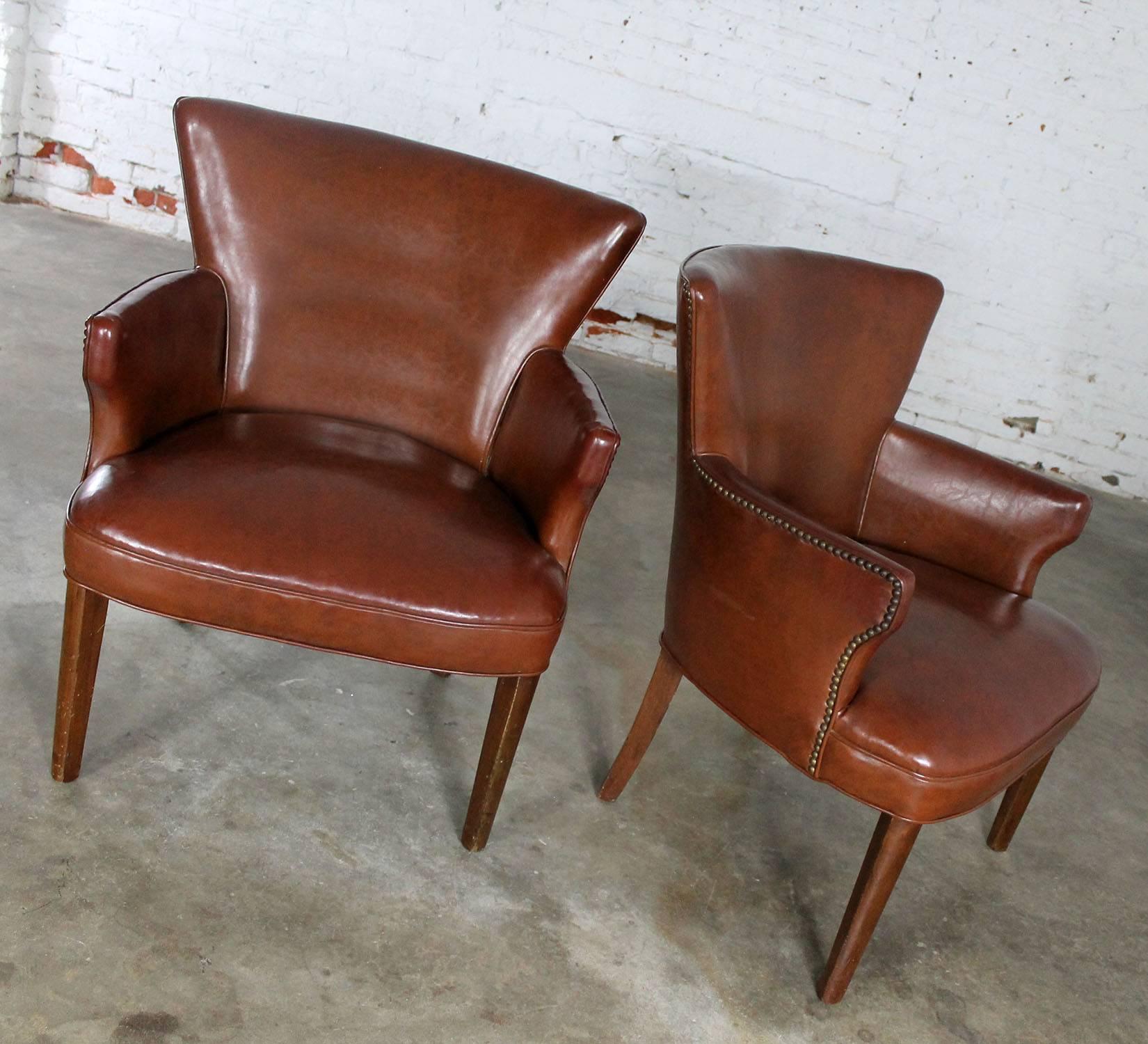 Petite pair of Art Deco armchairs with brown faux leather original upholstery and nailhead accent, circa 1940s. These great side chairs are in wonderful vintage condition. There are no tears or holes in the upholstery and the springs have been