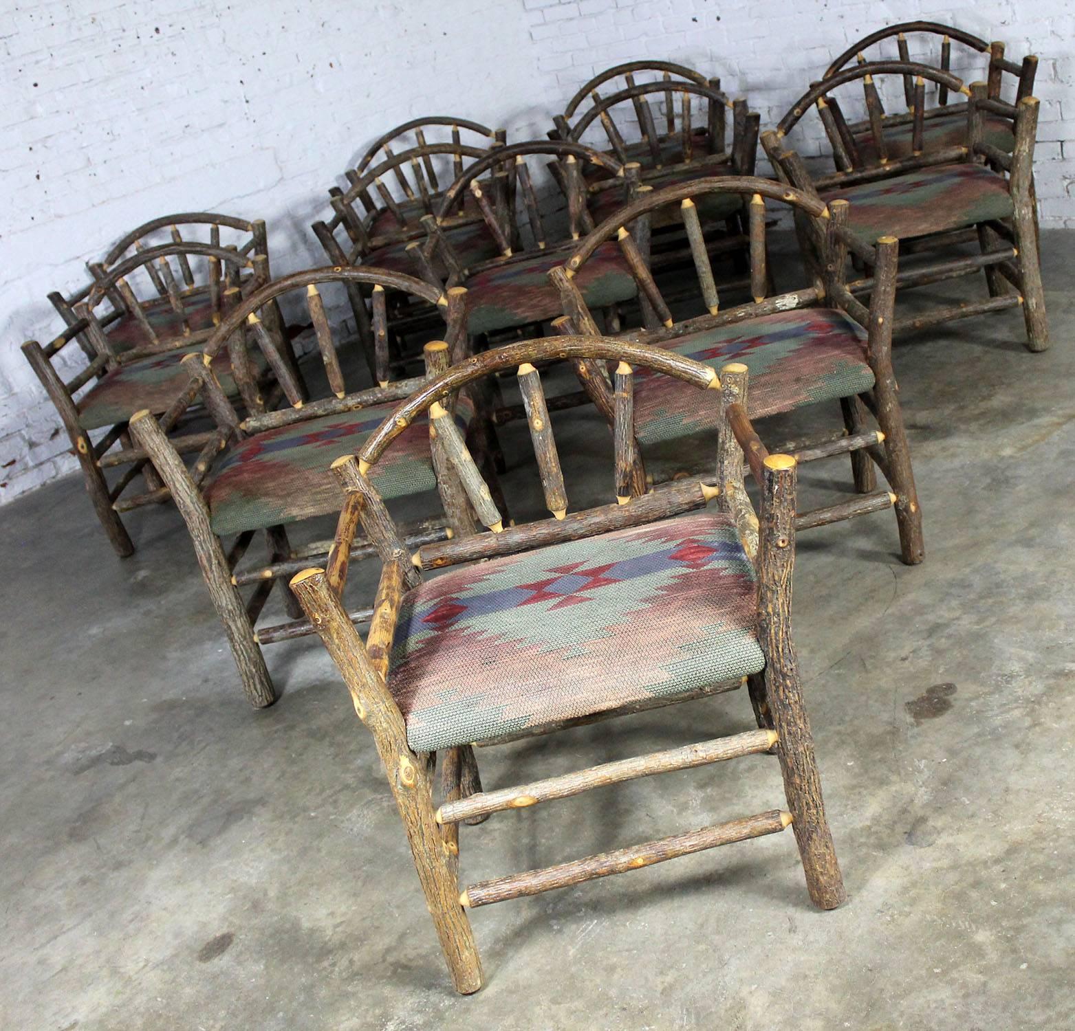 Awesome set of twelve rustic hickory armed dining chairs in the style of Old Hickory. These chairs are in exceptionally good condition. The seats are covered in a blue, green and wine colored western or cabin style upholstery. If the fabric suits