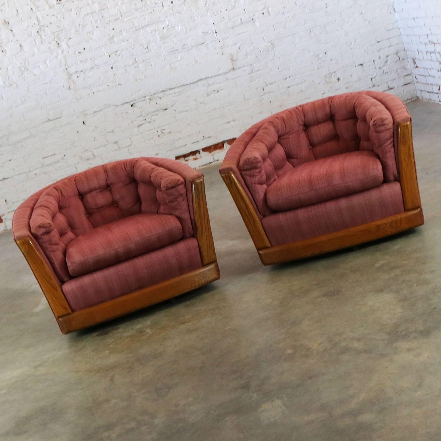 Unusual and awesome pair of modern swivel barrel chairs with oak trim done in the style of Milo Baughman or maybe Harvey Probber. They are in wonderful condition structurally and the wood trim is great as well; however, the original fabric does show