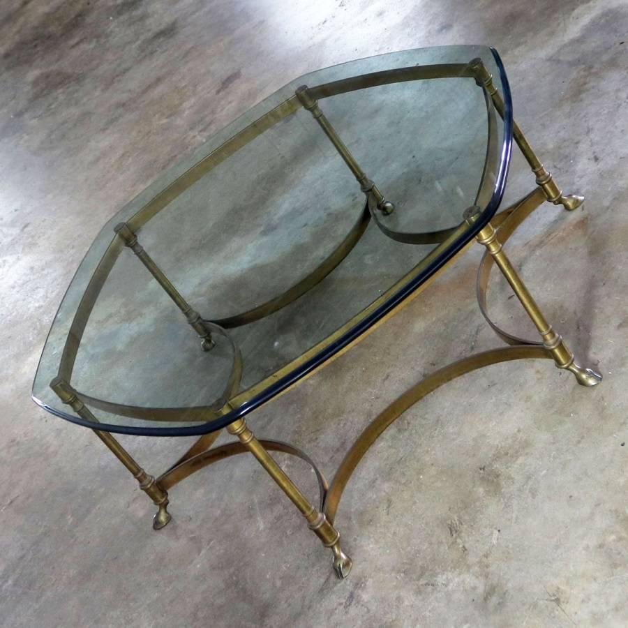 Fabulous antique brass and glass neoclassical or Hollywood Regency coffee table with rounded hexagon shape and cloven hoof feet. This table is in wonderful, circa 1970s vintage condition.

Whether your decorating style is neoclassic, transitional,
