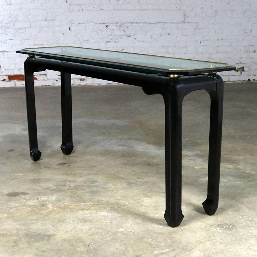 Very handsome console or sofa table in the style of James Mont. Black lacquer Asian style base with brass trim and glass top. This table is in fabulous vintage condition and circa 1970s.

For your consideration an incredible circa 1970s sofa or