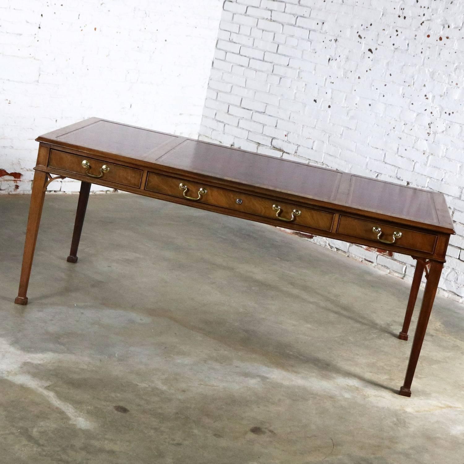 Very handsome vintage Chippendale style executive writing desk in mahogany with gold trimmed leather top from the Collector’s edition by Baker Furniture. This desk is in wonderful vintage condition; however, not without the patina of small nicks and