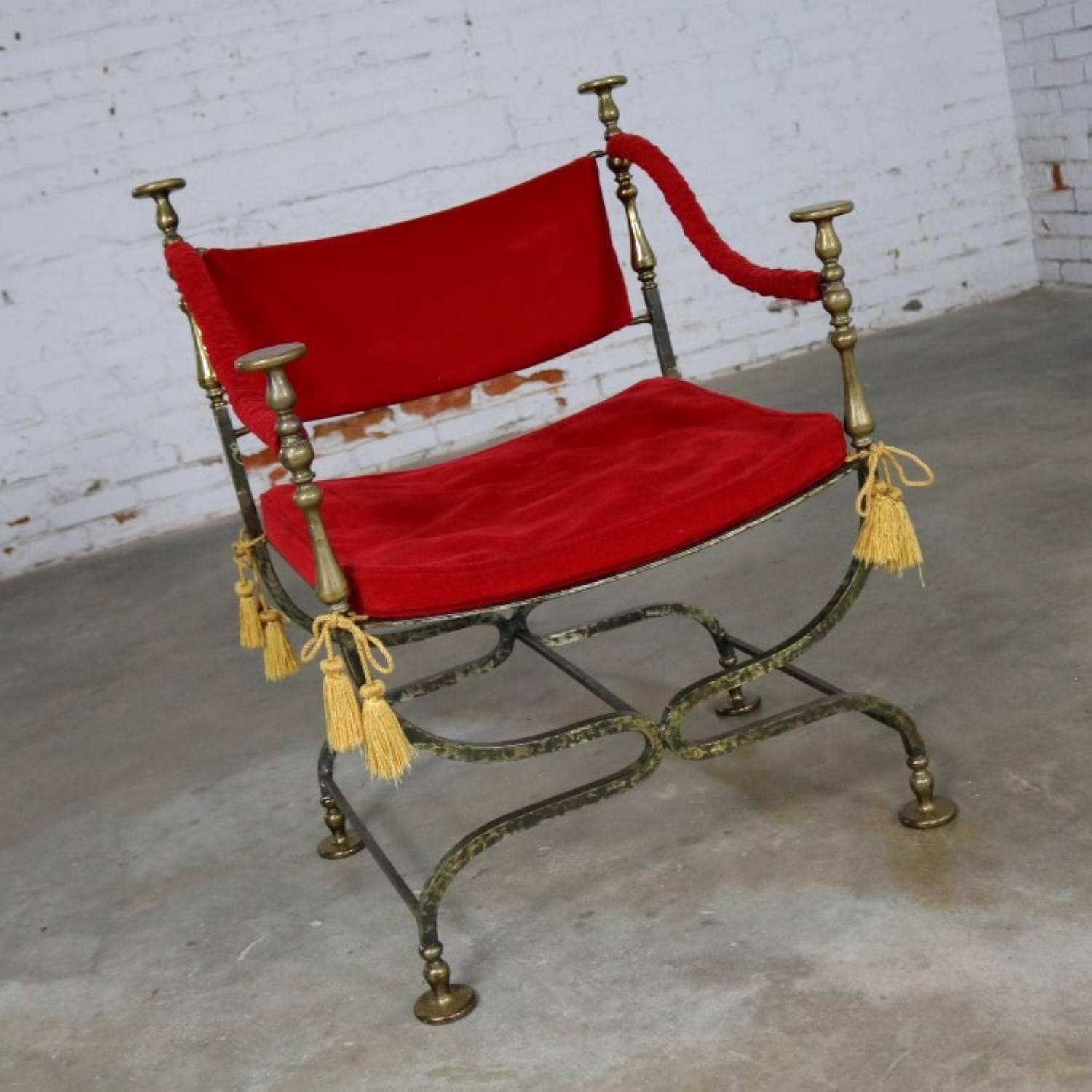 Stately and wonderful curule or Savonarola chair comprised of wrought iron and cast brass with red velvet. This chair frame is in perfect and beautiful condition and the velvet fabric is in good vintage condition and could be used; but, the foam in