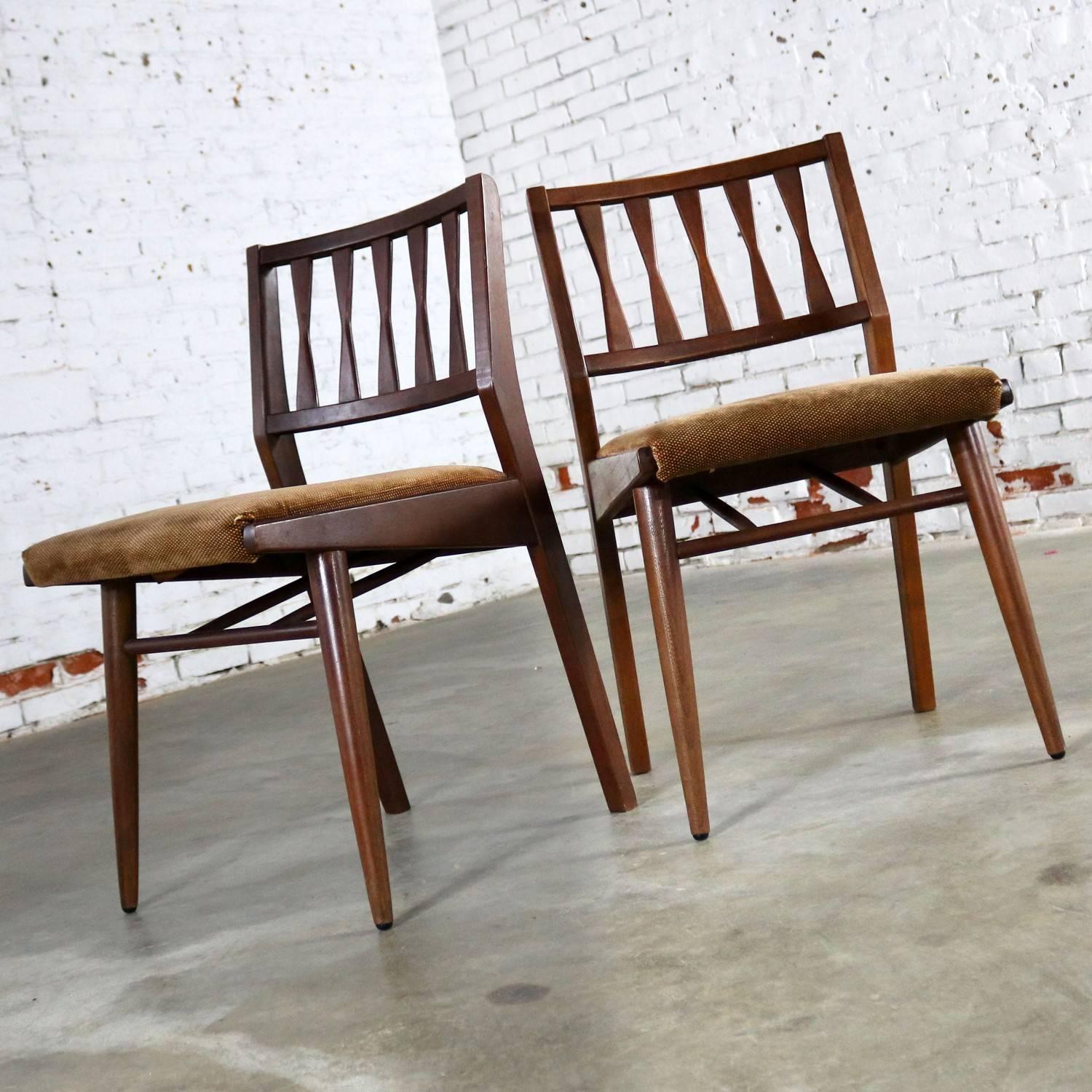 Great pair of armless dining side chairs in walnut with upholstered seats by the Holman Manufacturing Co. They are in wonderful vintage condition with what looks like the original upholstery with normal wear for age and no outstanding flaws, circa