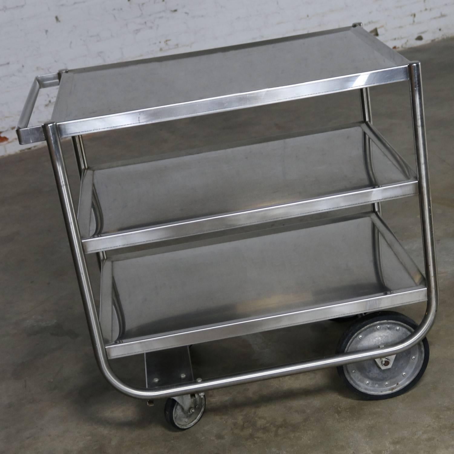 Awesome vintage Industrial three tier heavy gauge stainless steel rolling cart. It is in wonderful vintage condition with a nice overall patina to the stainless which includes small scratches and dings. The wheels are galvanized with hard rubber