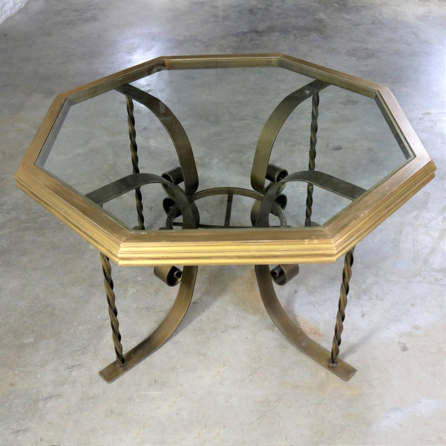 Handsome wrought iron Hollywood Regency style dining table with a wonderful octagon shaped wood rimmed glass top. It is in fabulous condition. The iron base has its original gold painted finish, which with age and use has gained a marvelous patina