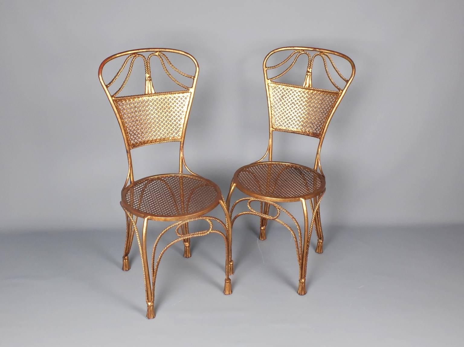 A single very decorative chair made of a cast and worked base metal that have been painted and gilded, showing signs of wear and rubbing that reveal the base red-ochre colour in places. The motifs of tassels and twisted cord have been incorporated