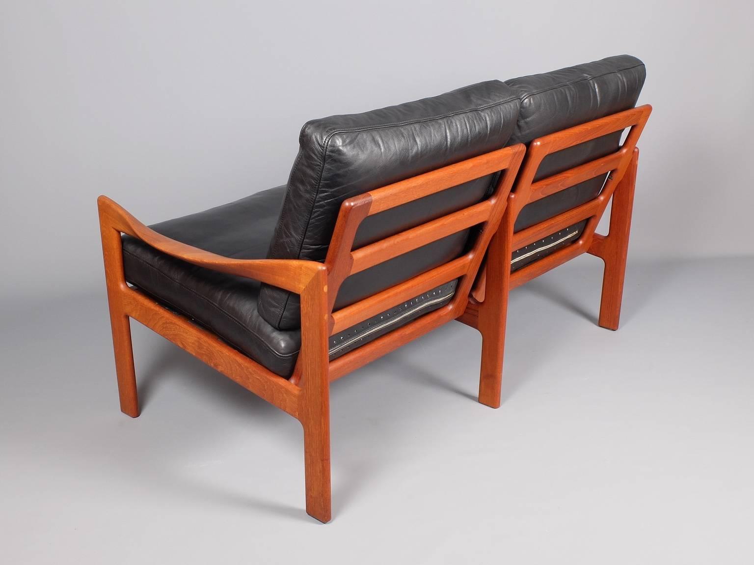 A two seat teak framed sofa designed by Illum Wikkelso and produced by Eilersen, Denmark, circa 1960. The original leather cushions have been cleaned and renovated and are in very good condition and have all been fitted with new feather interiors.