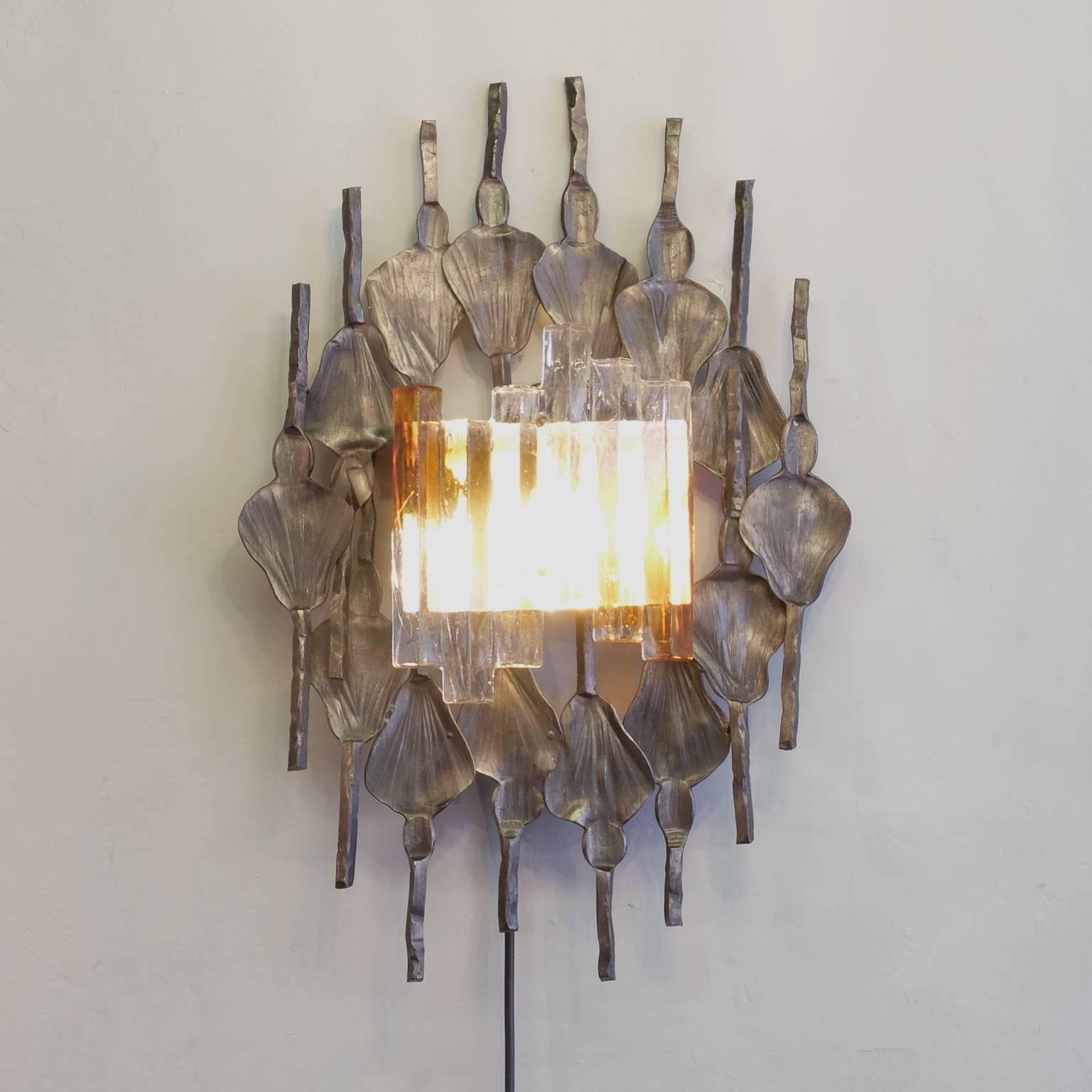 A very large wall sconce from Swedish design company A & E Design, circa 1970, in the Brutalist style and manufactured in Germany by A & E Leuchten. The hand wrought iron surround has a good patination and is set off by the Murano ice glass with its