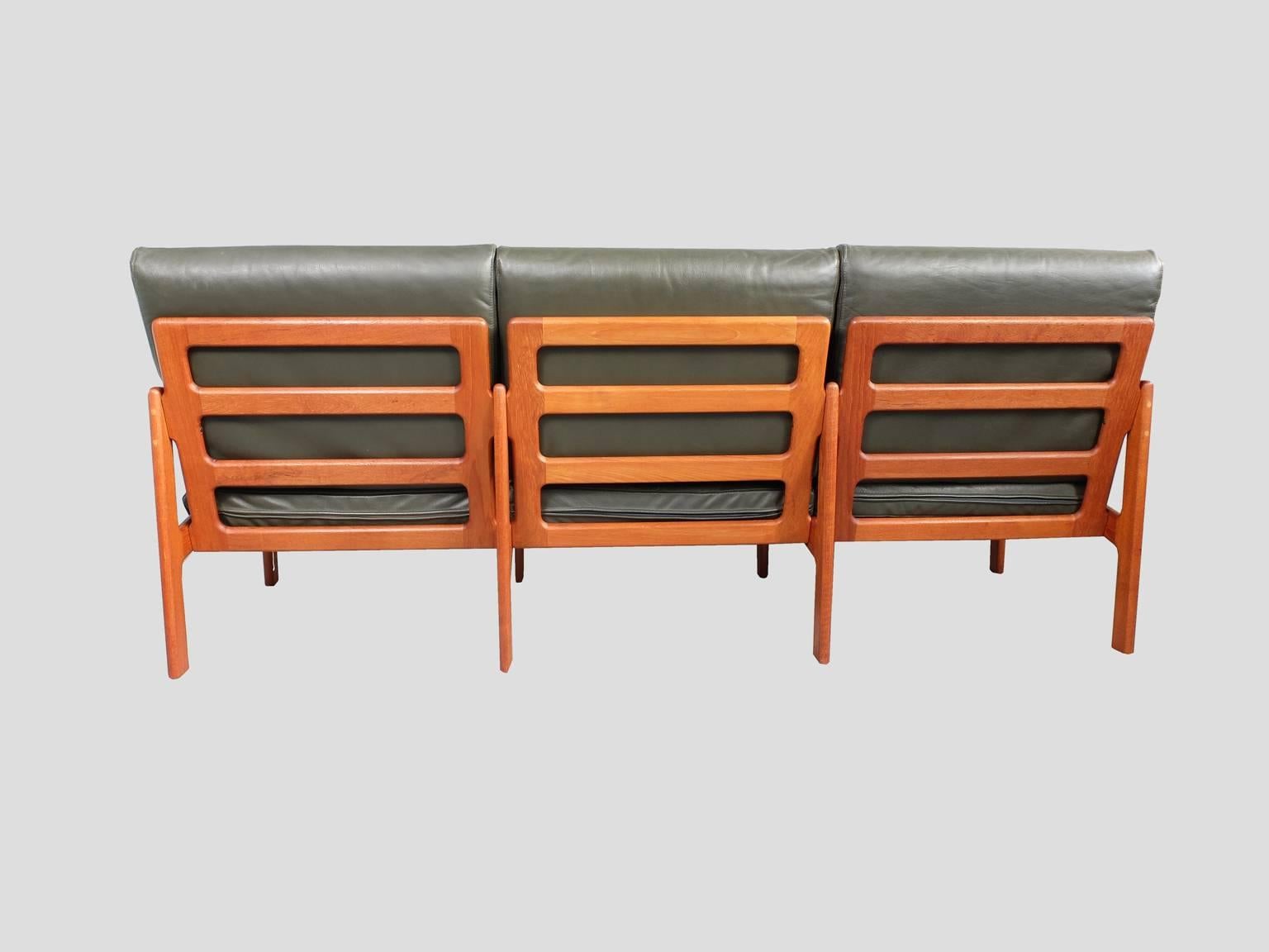 A three-seat teak sofa designed by Illum Wikkelsø and produced by Eilersen, Denmark, circa 1960. The original dark green leather is in very good condition without significant wear, fading or marking. The leather cushions will have new interiors