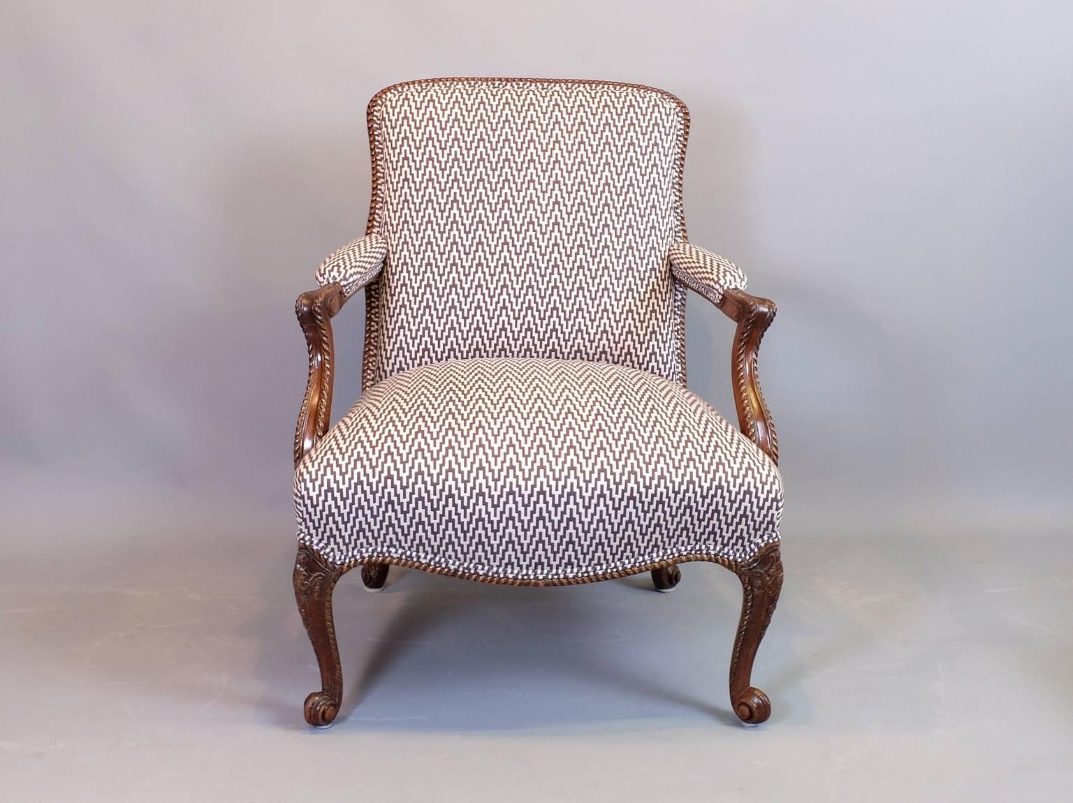 A pair of carved mahogany English library chairs, circa 1900 that have been re-upholstered in a contemporary fabric. These are high quality chairs with well carved frames and cabriole front and rear legs. The panelled and framed backs make these