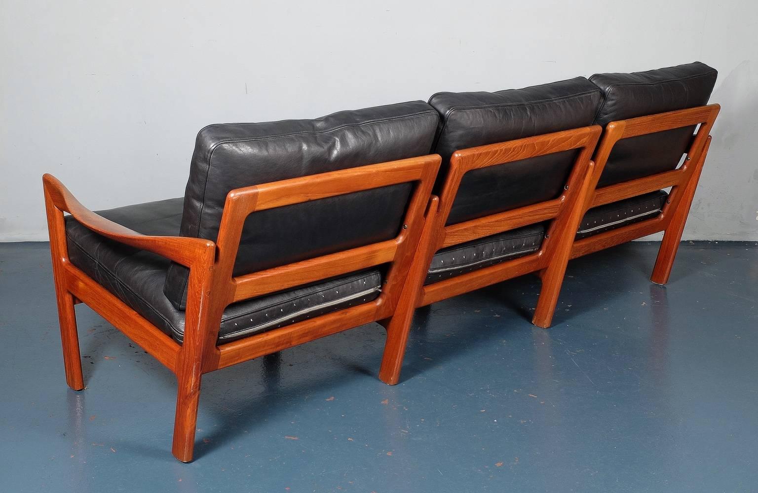 A three-seat teak sofa designed by Illum Wikkelsø and produced by Eilersen, Denmark, circa 1960. The original leather is in very good condition without significant wear, fading or marking. The black leather cushion interiors have been replaced with