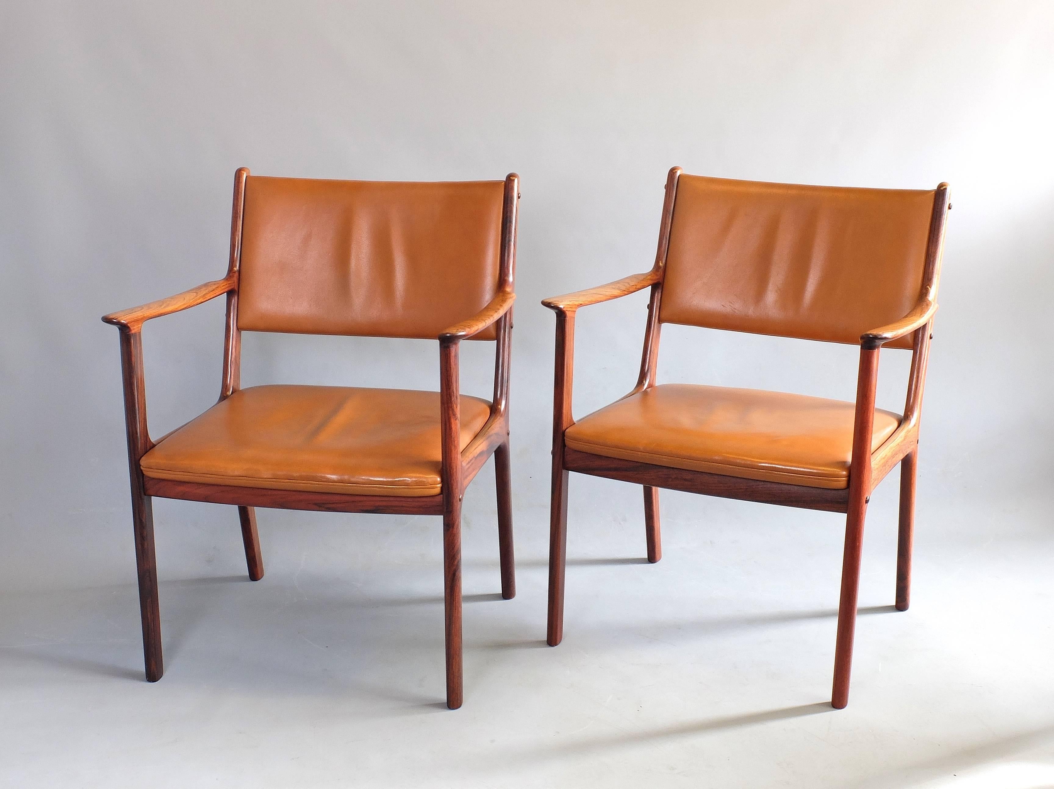 A pair of armchairs designed by leading Danish furniture designer Ole Wanscher, circa 1960, and produced by Poul Jeppesen. This is model PJ412 in beautifully grained hardwood. The chairs are upholstered in the original cognac coloured real leather,