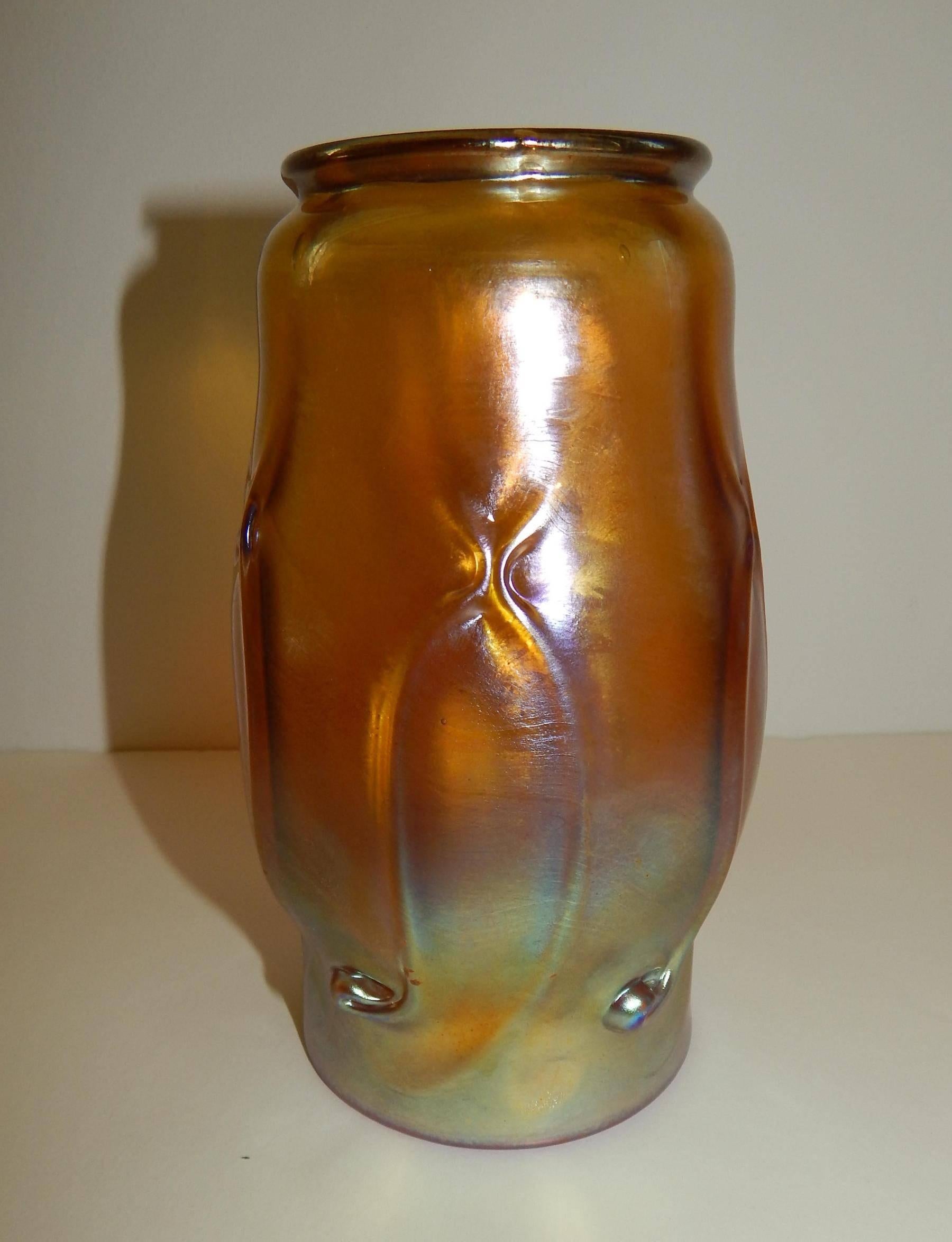 Iridized favrile vase by Tiffany Studios. 
A rich gold with highlights of pink and blue. 
Around the body of the vase are small pulls to the glass (or prunts). 
Favrile glass was patented by Louis Comfort Tiffany in 1894. 
A beautiful piece in