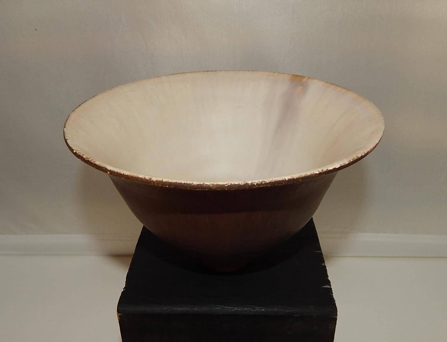 This gracefully flared ceramic bowl bears her traditional “feelie” soft glaze with large drips showing near the base.
Rich brown with cream interior. Measure: 3.5