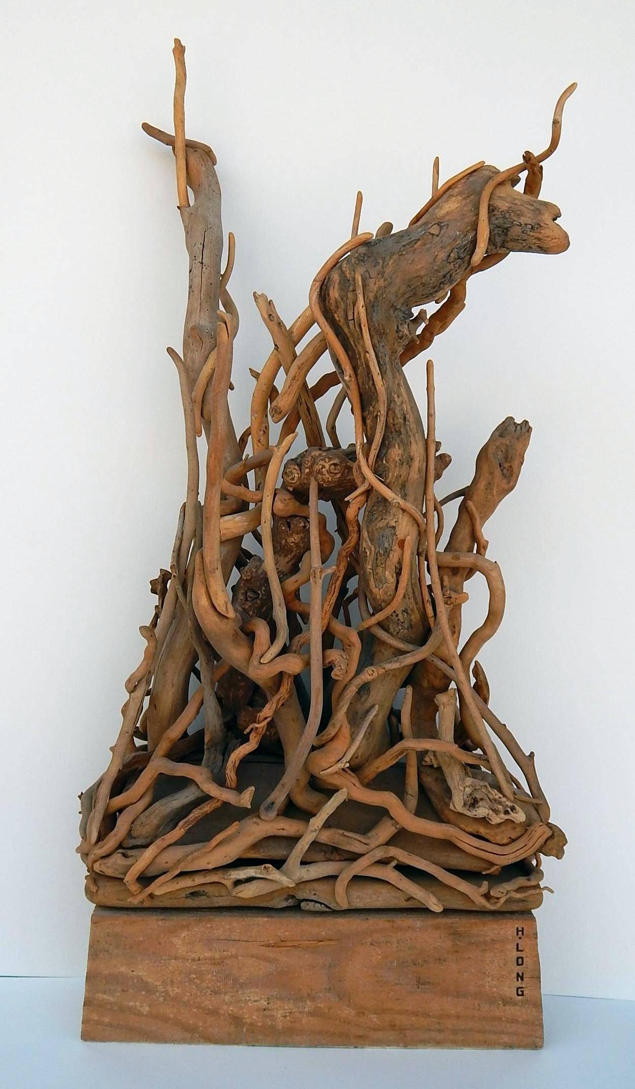 Accomplished artist Hubert Long created this striking display of found wood in 1977. 
He enjoyed some success with exhibitions at a gallery on Long Island in the 1960s and 1970s. 
The piece is signed “H. Long,” titled “JAS,” and dated 1977.