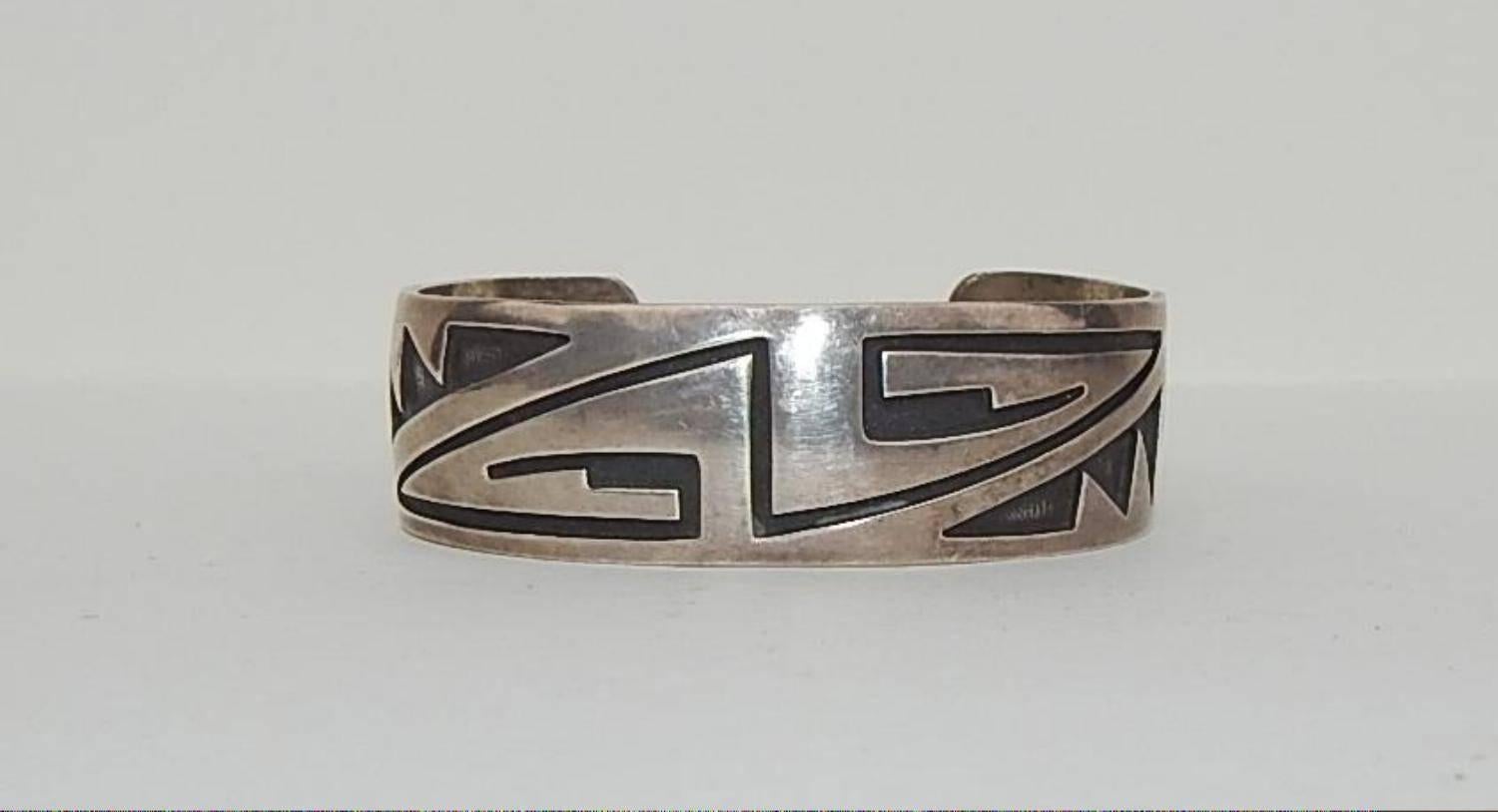 Beautiful sterling native American bracelet crafted by
Hopi Silversmith Eldon Siwingyumptewa Kalemsa, Sr.
of the Snow clan, who passed away in 1996.
Stamped with his cloud monogram and a sunface.
Band is 3/4