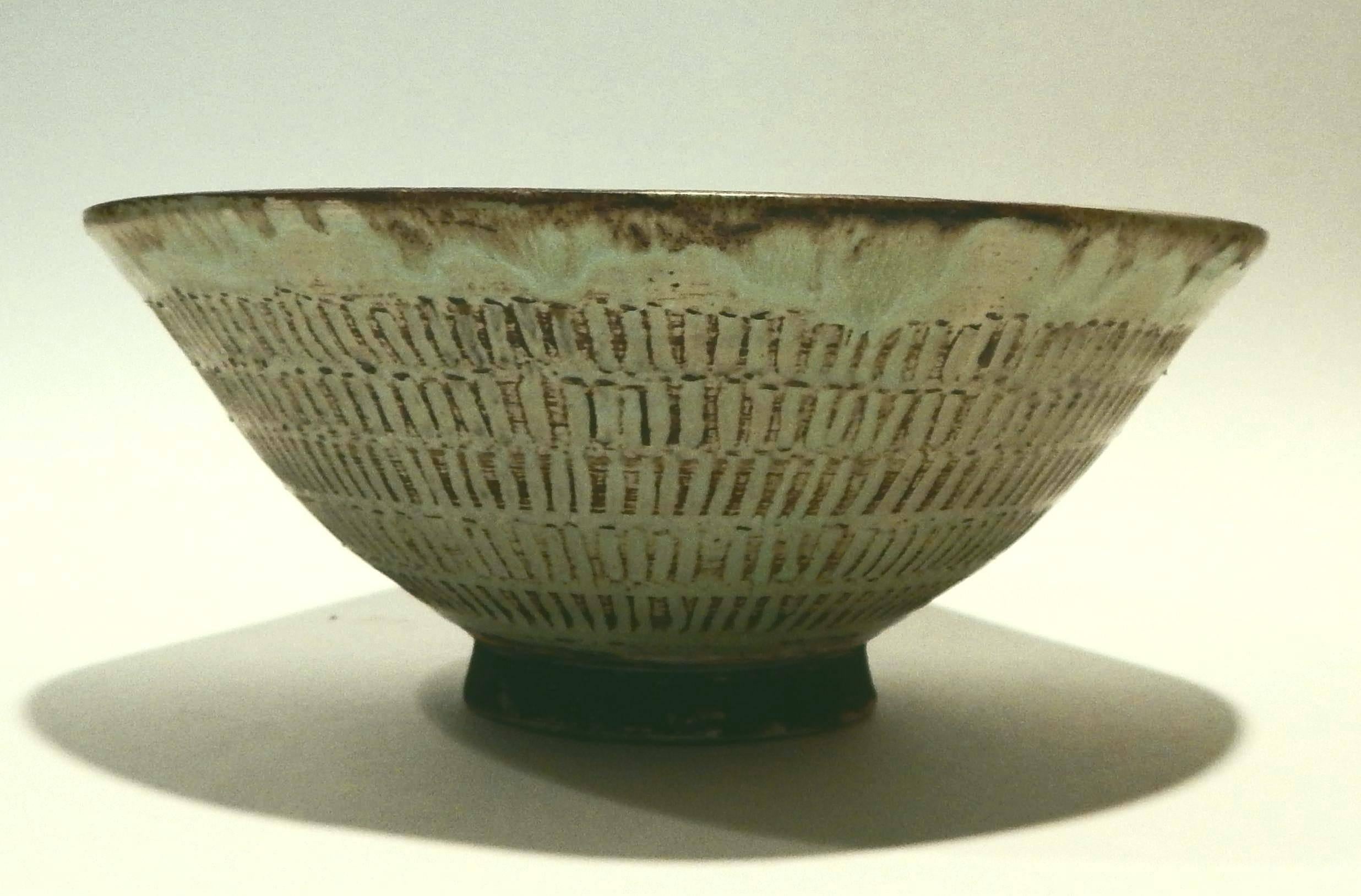 Flared pottery bowl with incised overall decoration to exterior.
Glazed in sea foam green with brown highlights.
Created circa mid-1950s, mint condition.
Measures 4.25