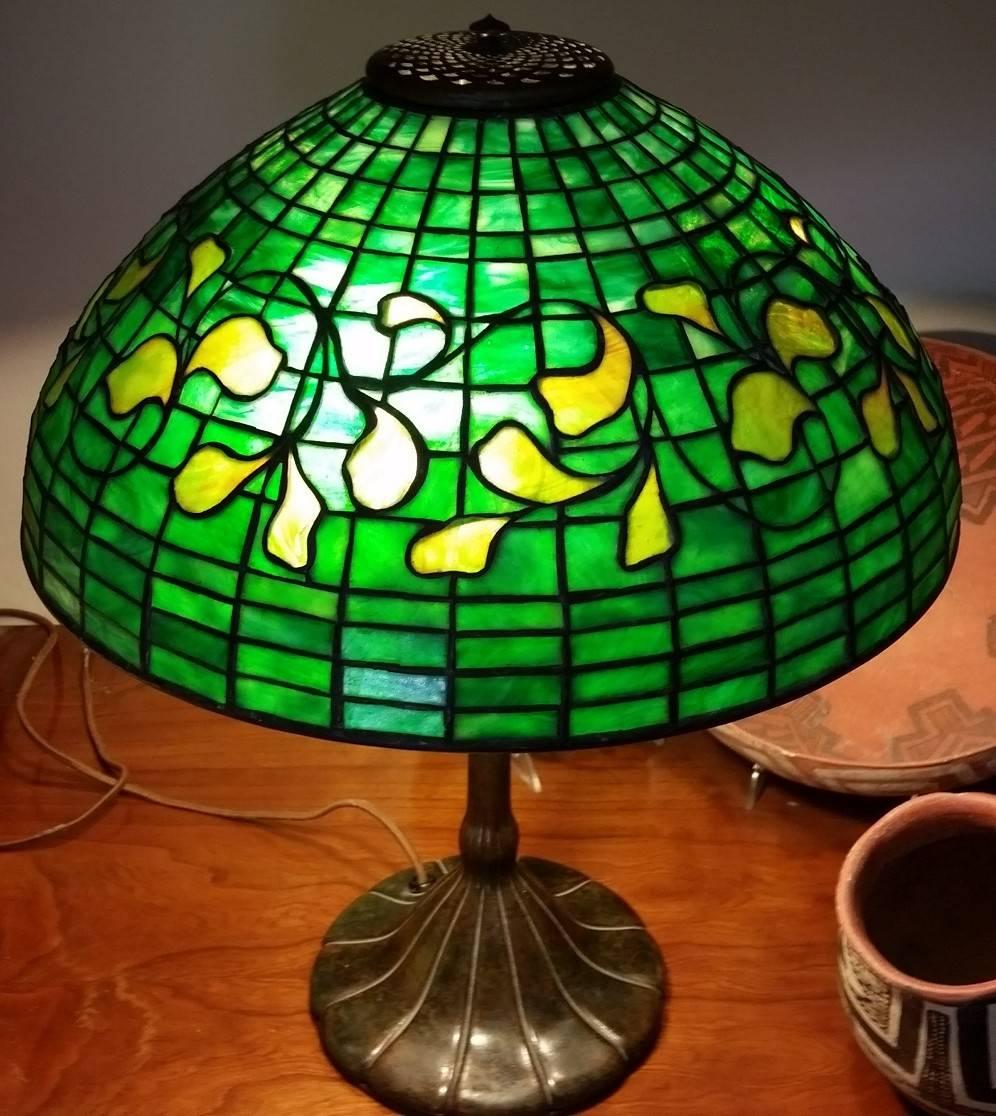 Beautiful Tiffany Studios table lamp in the swirling leaf pattern
on patinated bronze three-light base number 333.
Leaded glass shade measures 16