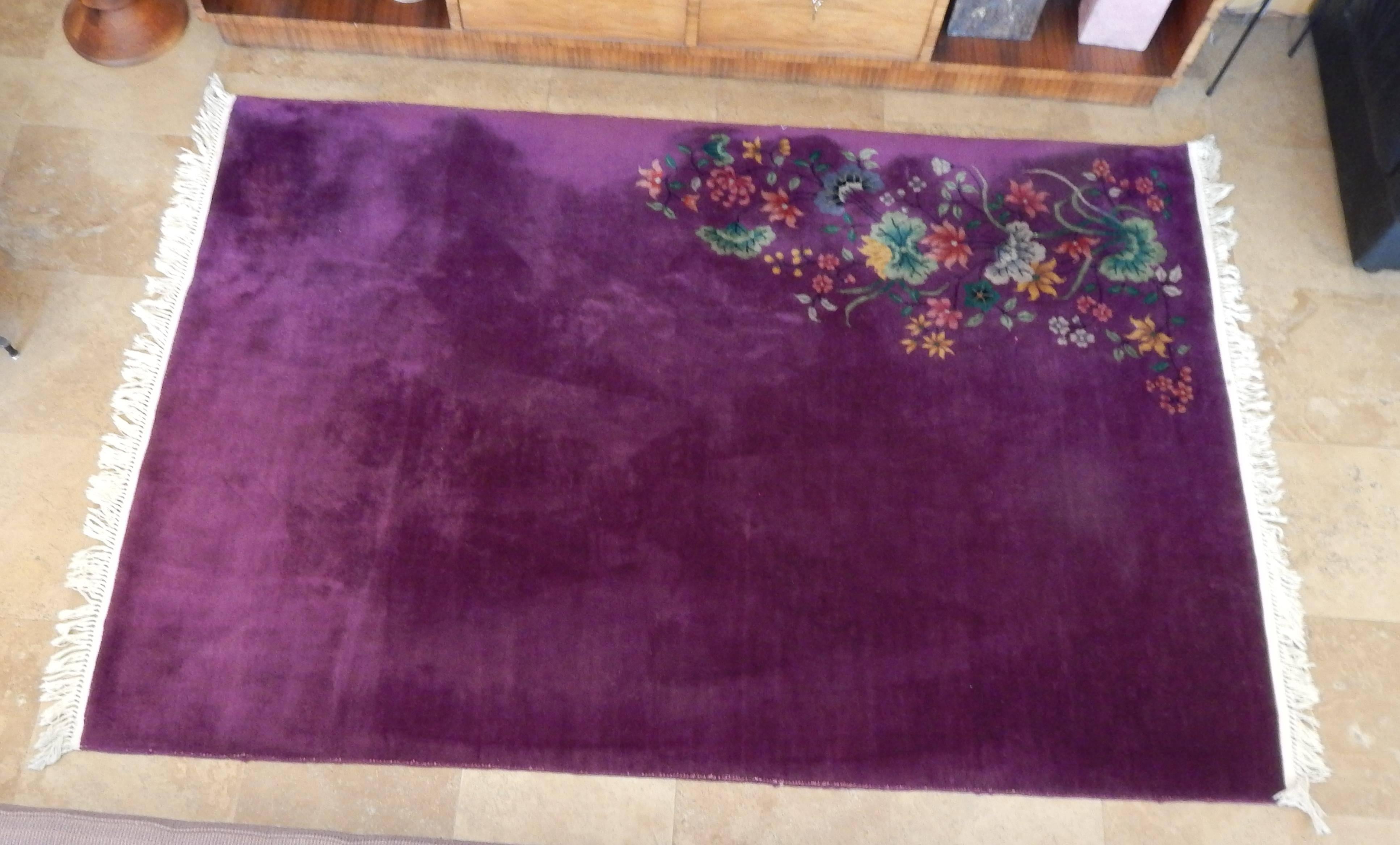 A fabulous early 20th century Chinese Art Deco wool rug in deep purple.
One corner bears an overlay of multicolored flowers in pink, green and blue. The colors are rich and bright and the rug is in very good condition.
No staining and negligible