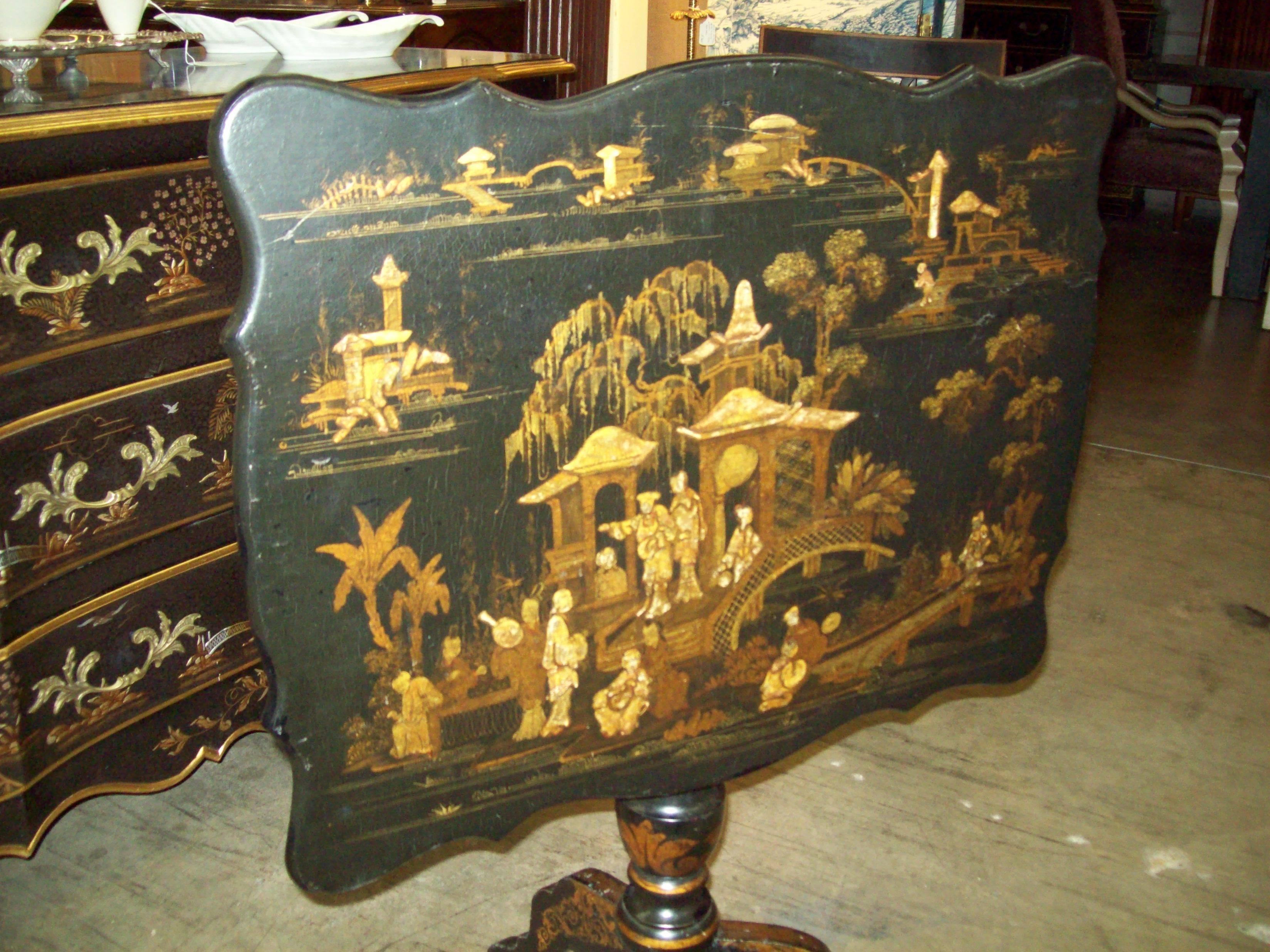 An English 19th century chinoiserie tilt-top rectangular table decorated in black and gold lacquer, with beautifully detailed shaped top and tripod base. Intricate gold lacquer designs appear intact with no apparent signs of flaking.
