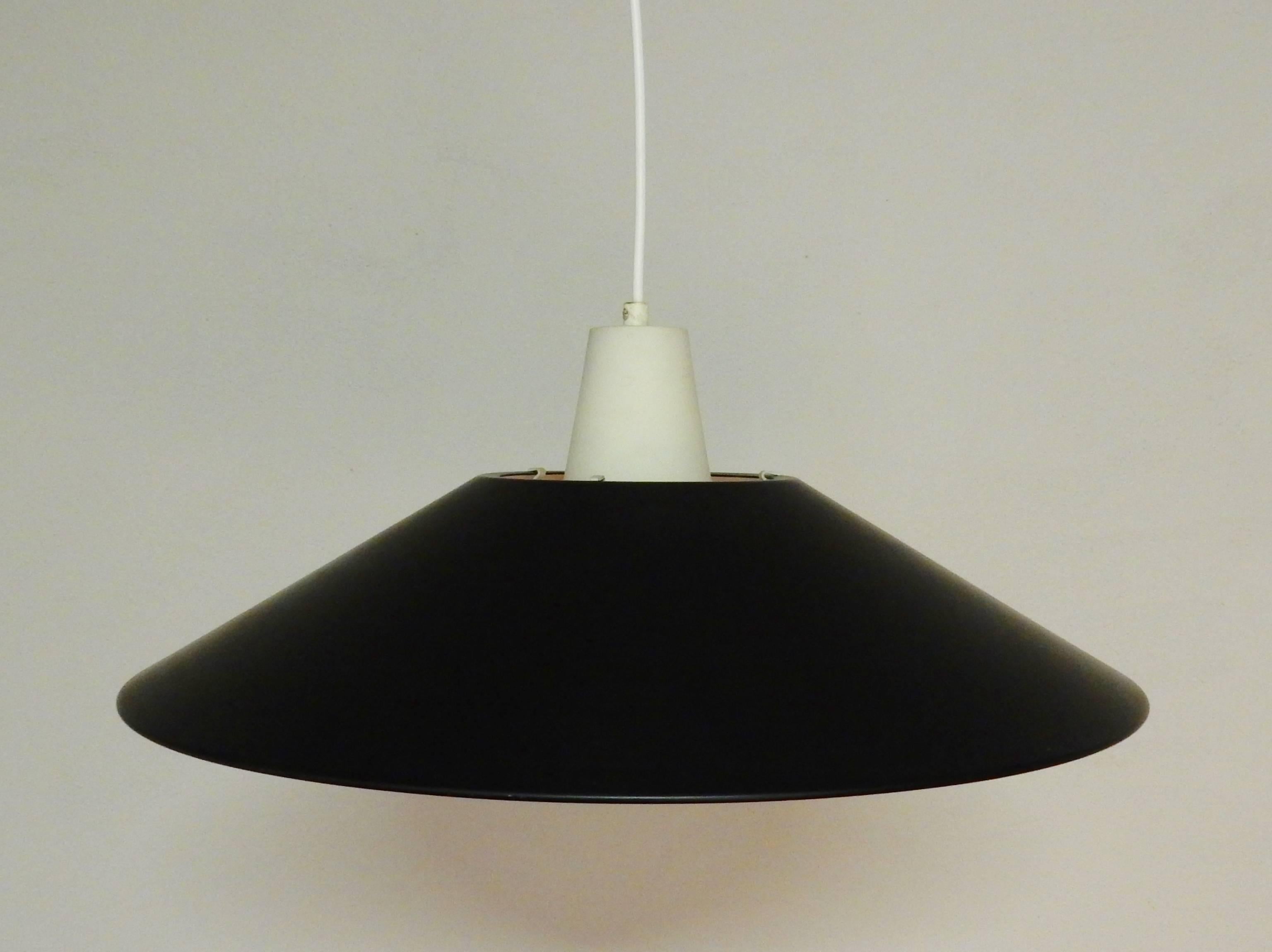 Metal pendant light in a black and white lacquer. A simple but yet very good looking light in a very good condition with some smaller signs of age and use, no dents. The black shade is held in place by the three metal clams/legs. The white metal top