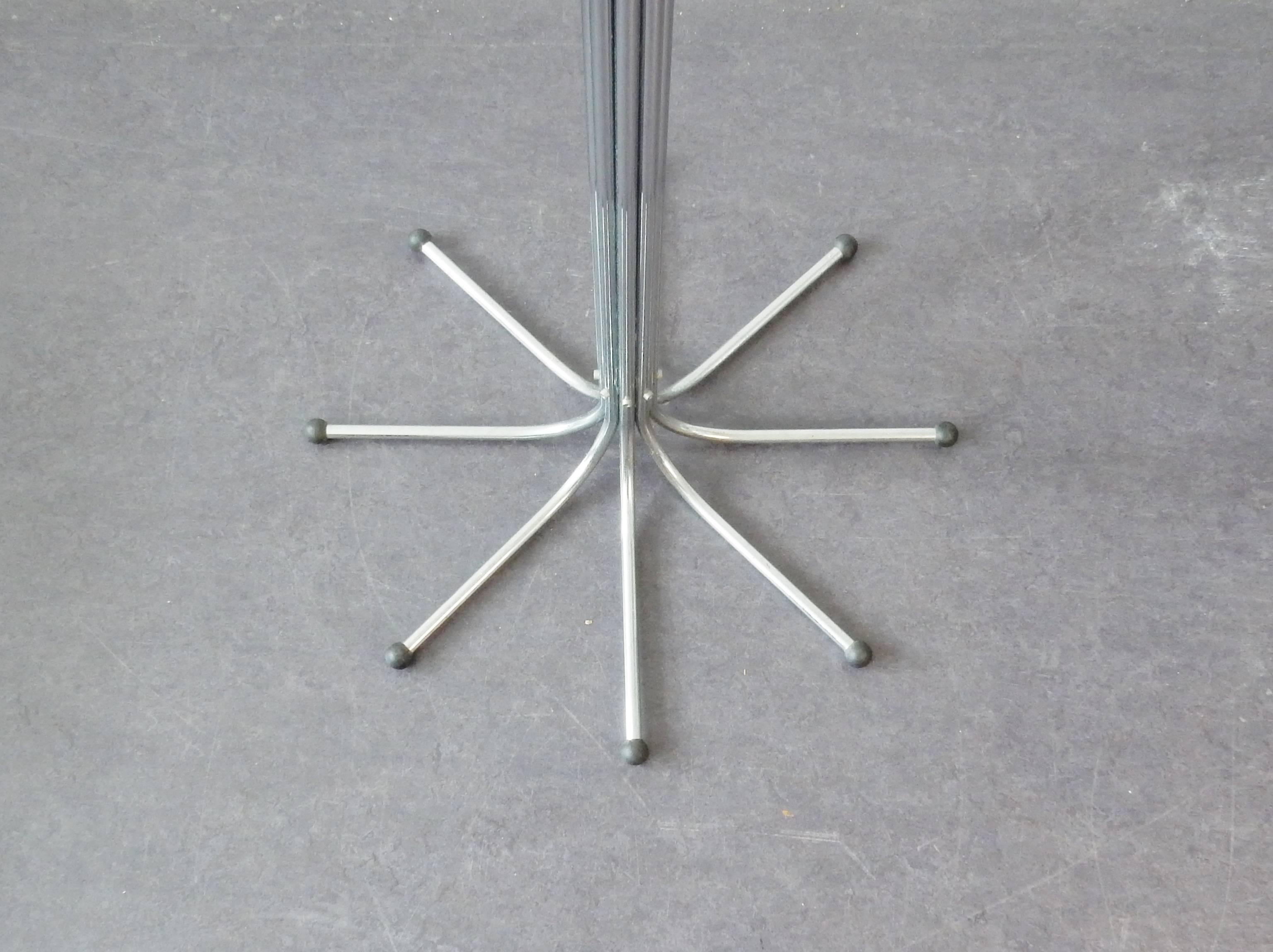 Coat rack inspired on a tree. 8 chrome metal pipes connected make a tree with 8 branches and a solid base of 8 roots. Each branch has 2 extra knobs and this makes it a very extensive coat stand. 
A design by Sidse Werner for Fritz Hansen from 1971.