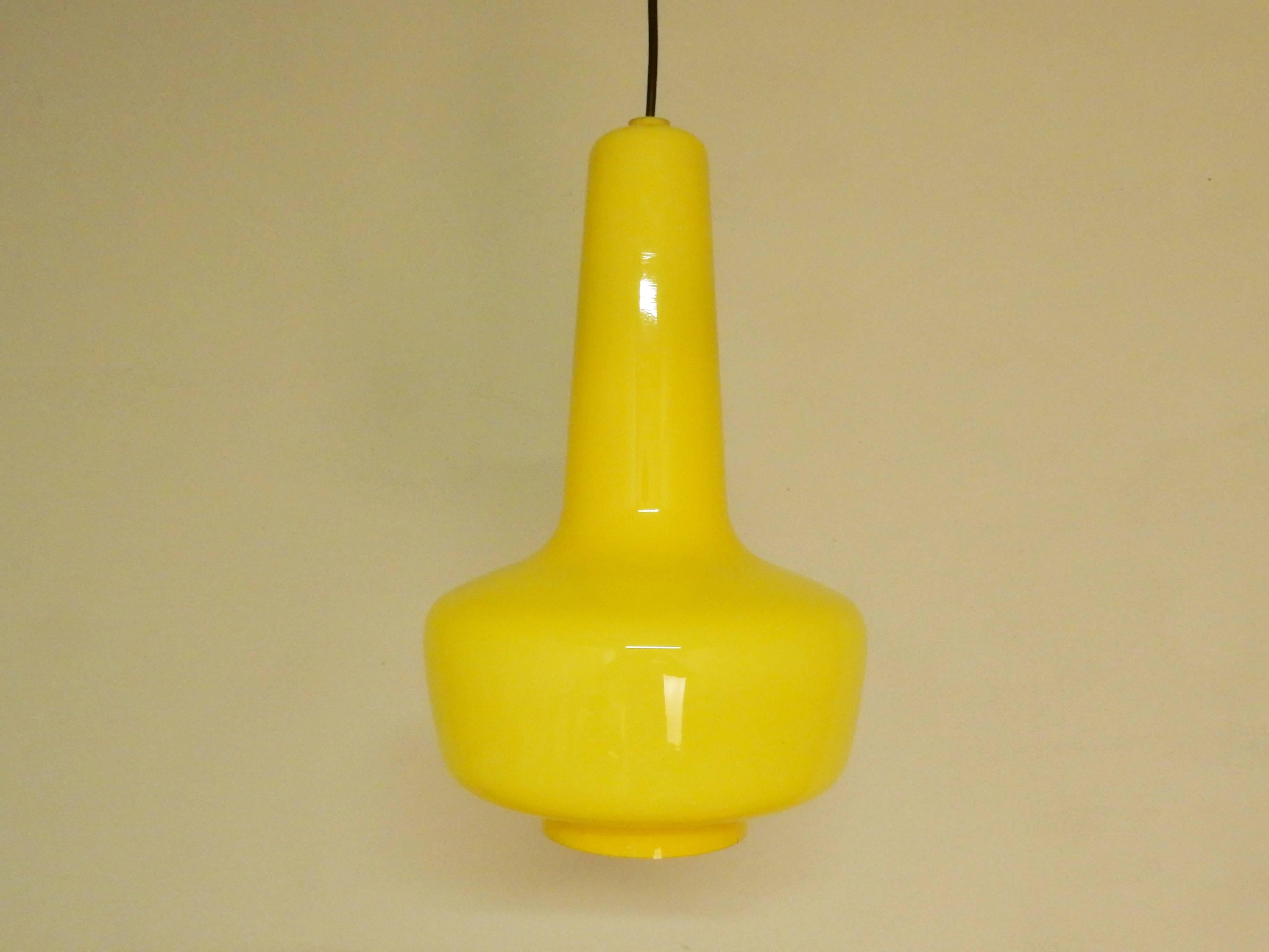 Very goodlooking pair of two glass pendant lights. Both are in a very good condition. The glass is of a bright yellow on the outside and the inside is of white opaline glass. The to soften the light. 
A design by Jacob E. Bang for Fog og Mørup from
