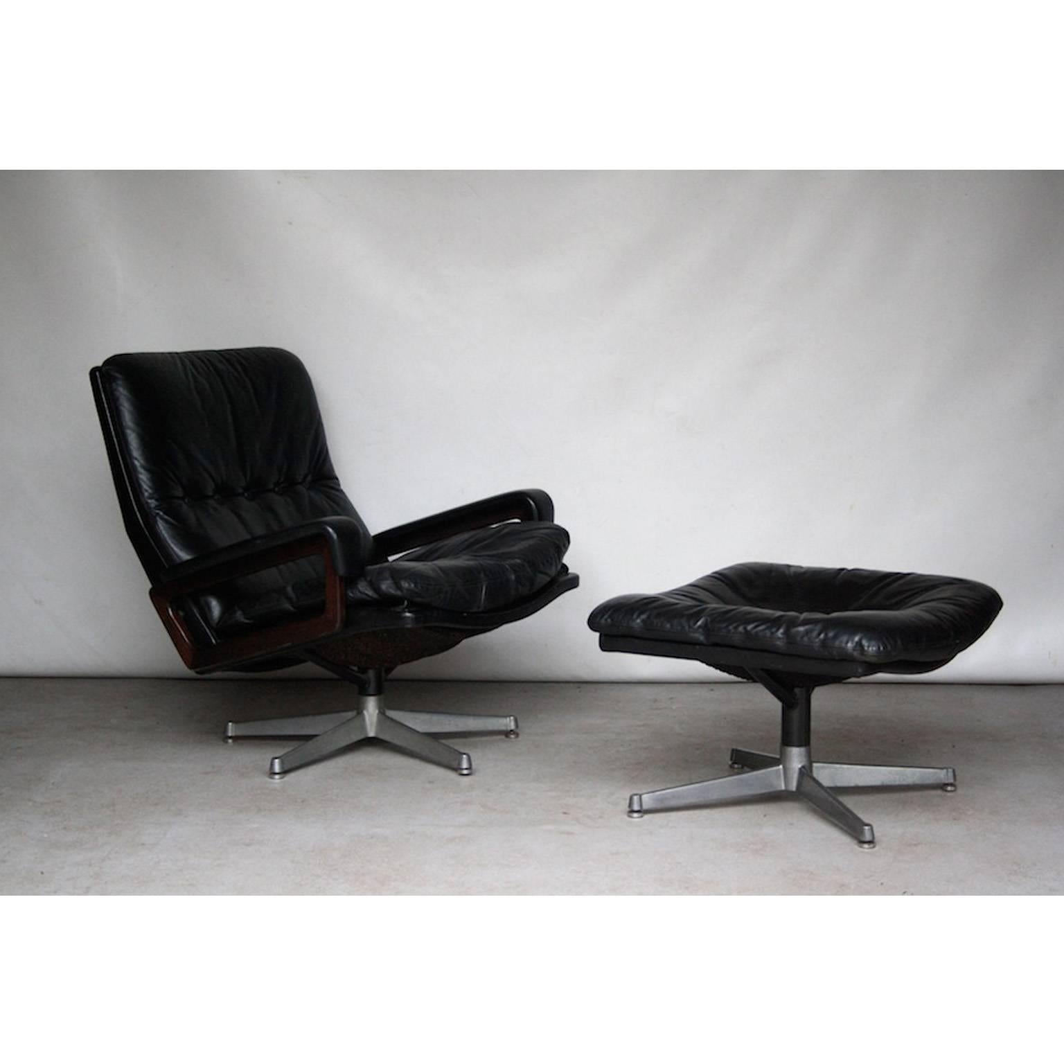 High quality lounge chairs and ottoman in black leather. The chairs have a solid and heavy iron base and armrests of rosewood upholstered in leather. The chairs and ottoman are made by Strässle which is comparable to the also Swiss De Sede.

Two