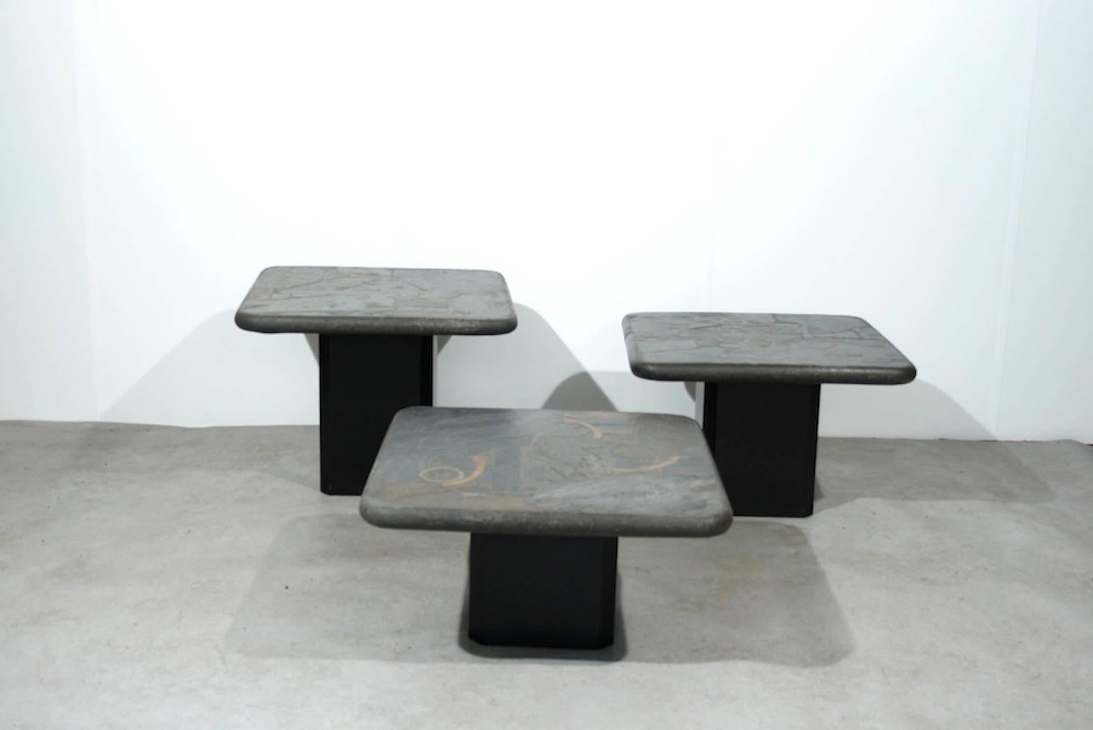 Matching trio of heavy stone top coffee tables on a wooden base. Signed by M. Kingma, the son of Paul Kingma. 

The tables come with an certificate.

They tables varies in three differrent heights:

Width: 60 cm
Length: 60 cm
Height: 31 - 39