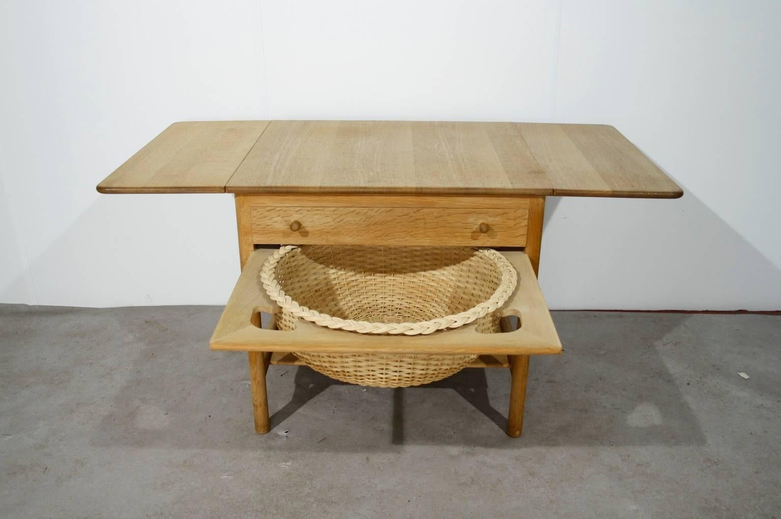 Oak sewing table with two drop leaves, a drawer and rattan basket.
In good condition.