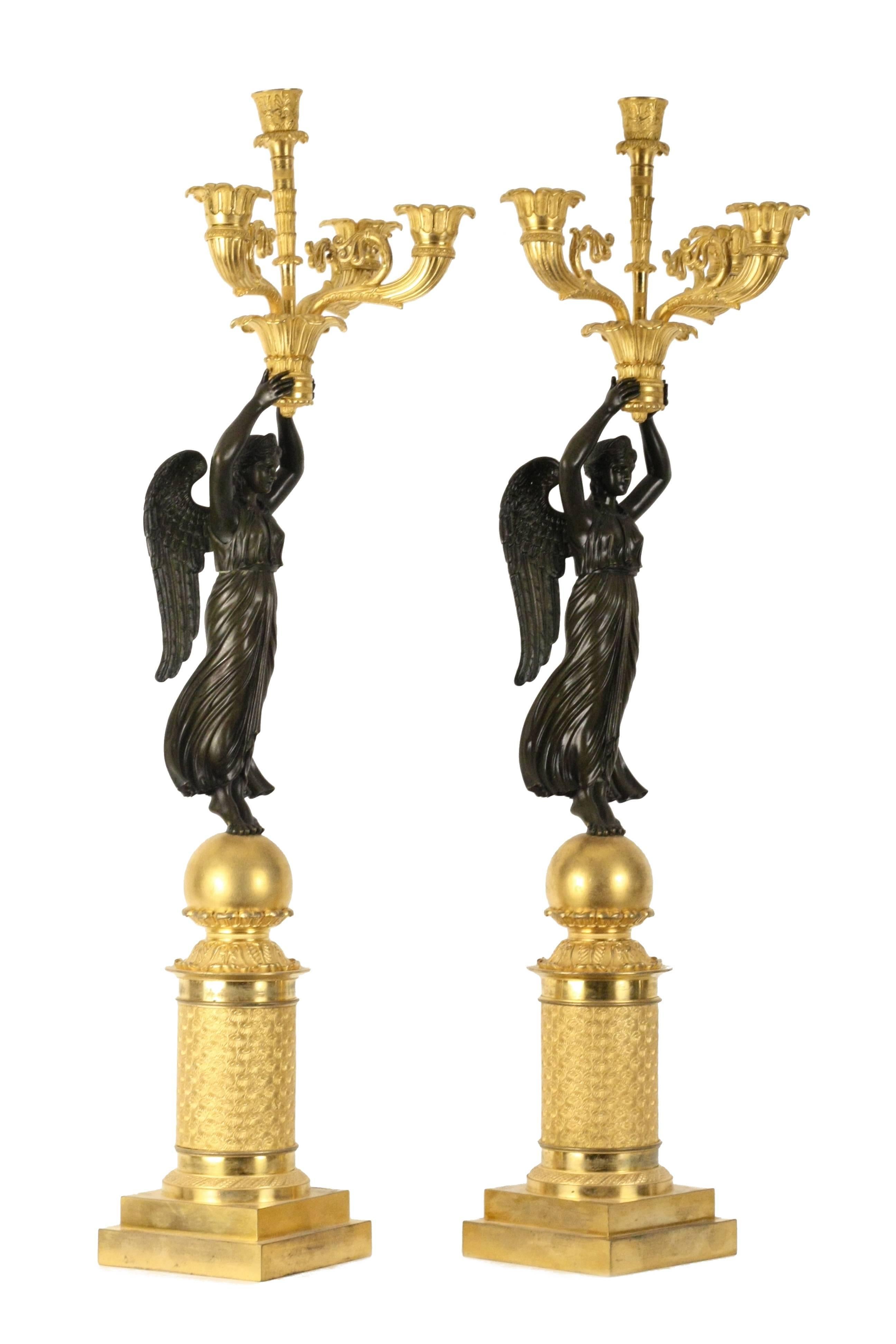 Pair of French Empire style gilt and patinated bronze four-light candelabra raised over the allegorical 'a la Victoire.' Highly detailed cast is in the distinct manner of Pierre Philippe Thomire (French, 1751-1843) after the original design by