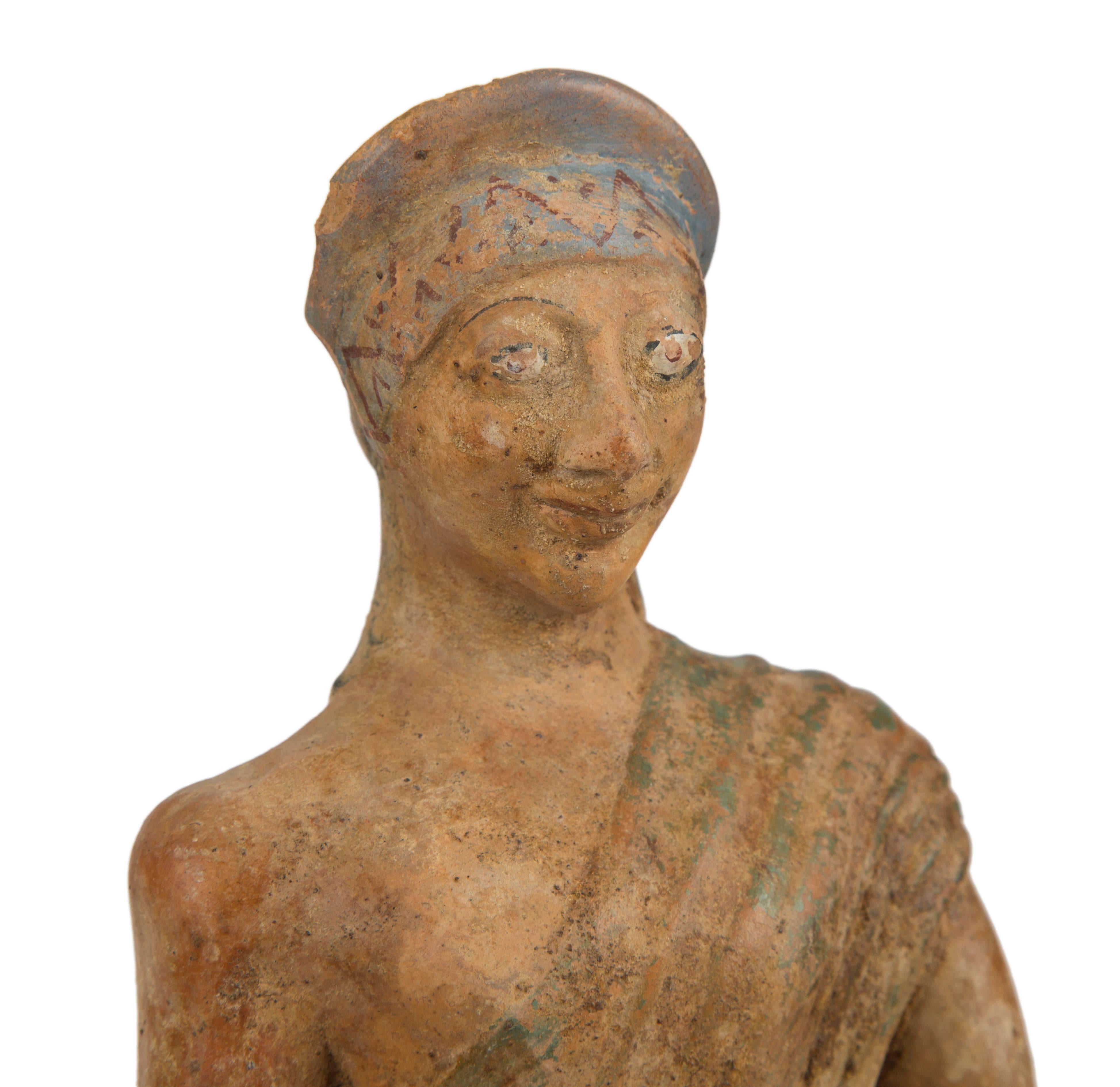 Terracotta statuette of a draped standing woman holding a dish.