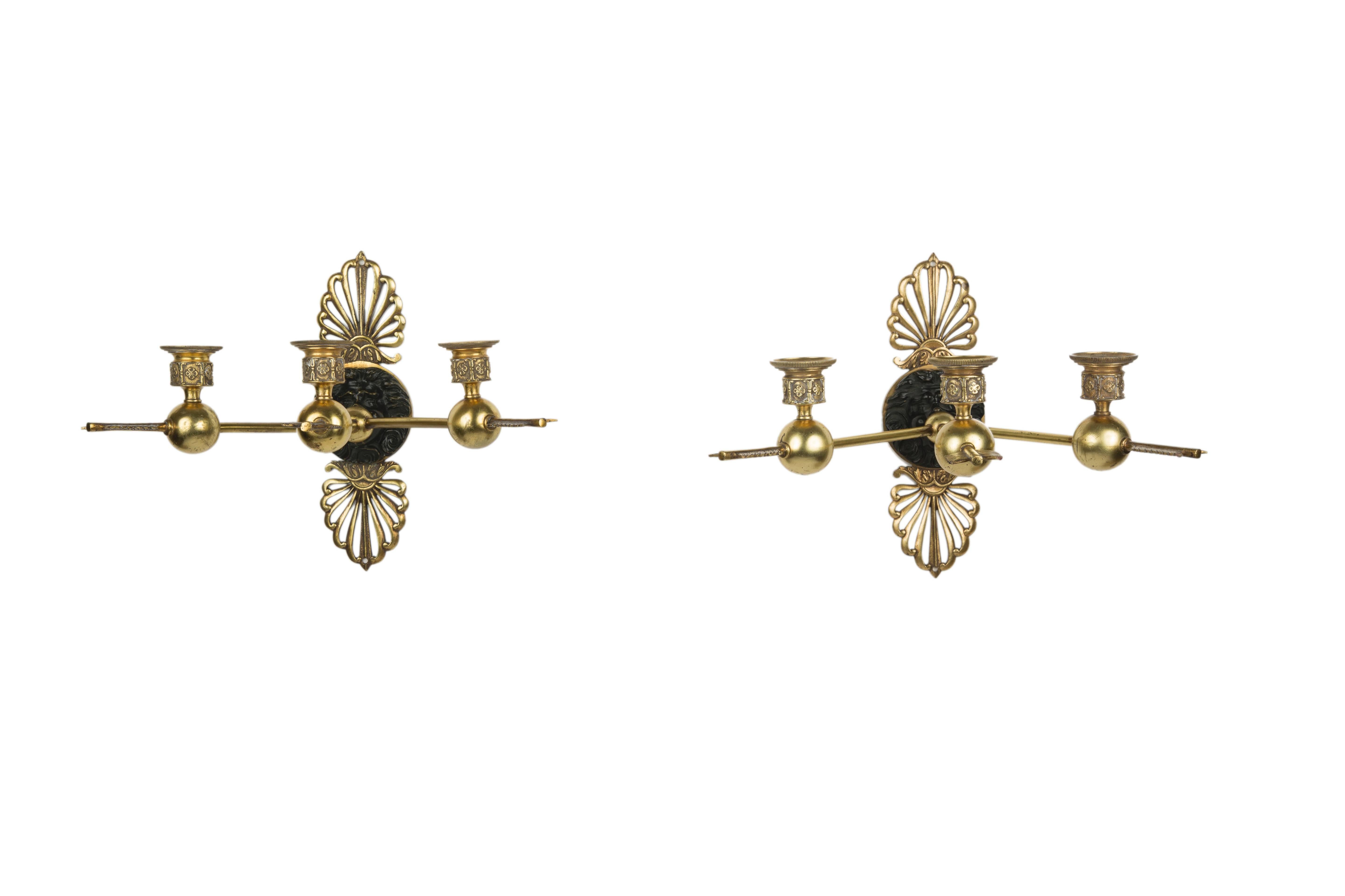 Pair of three-arm gilt bronze sconces each with arrows extending from a central patinated bronze figural plaque, France, Early 19th century.