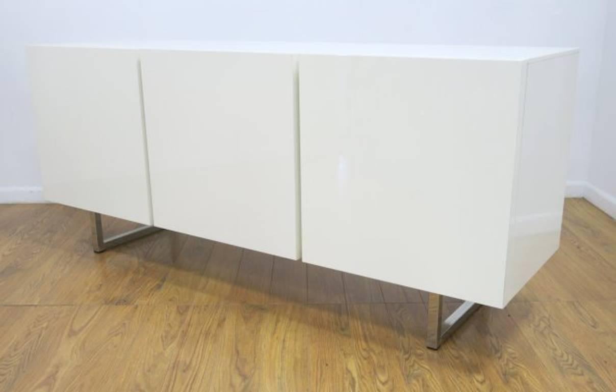 Lacquered white inside and out, this beautiful minimal credenza has two compartments with three push-pull handle less doors and two sturdy tempered transparent glass shelves.
    