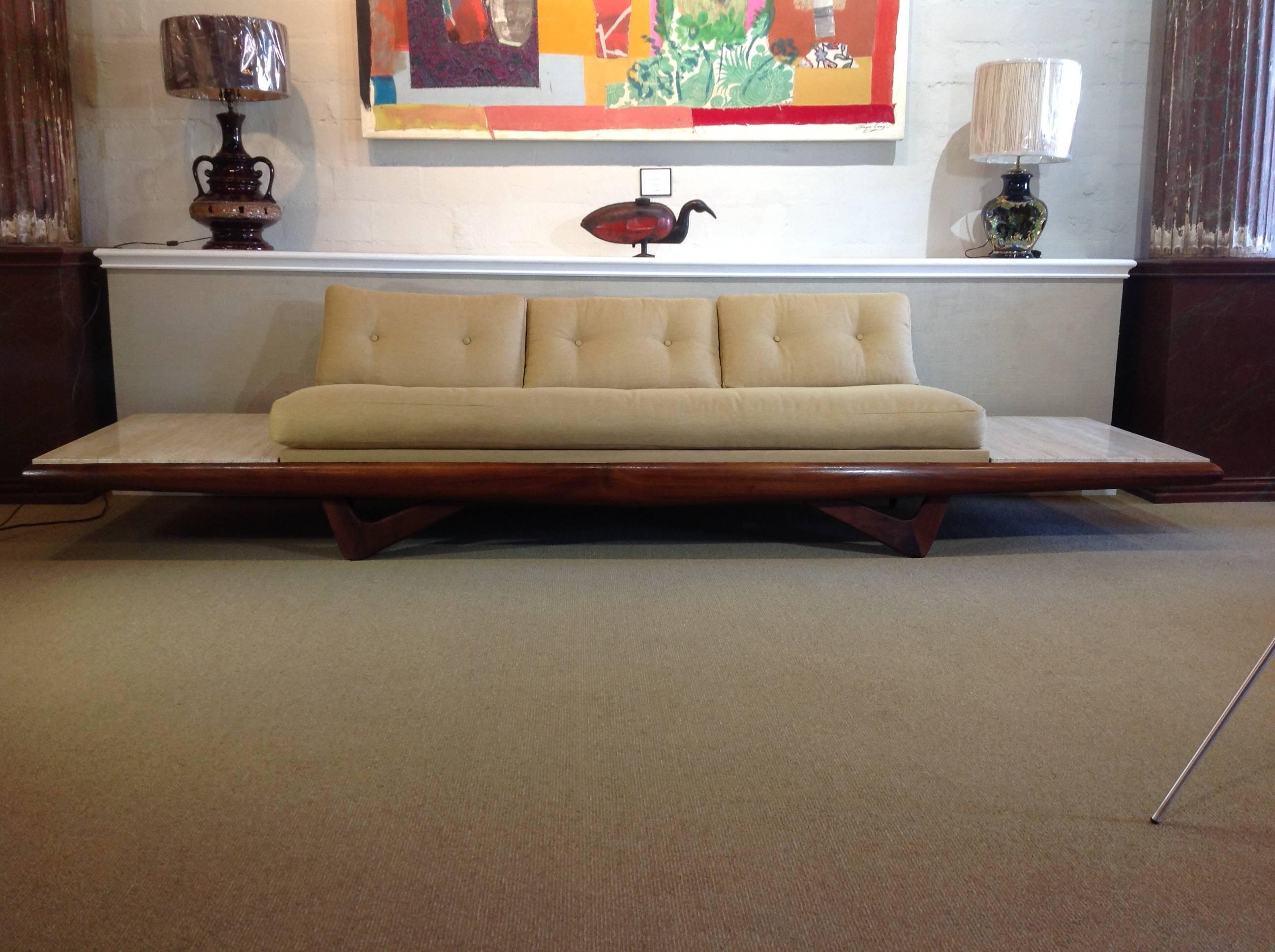 1950s sofa by designer Adrian Pearsall. This model was manufactured with the rarer "atomic " style feet. Rich walnut wood, with Roman travertine stone tabletops on each side. Newly upholstered with quality, light-beige fabric in