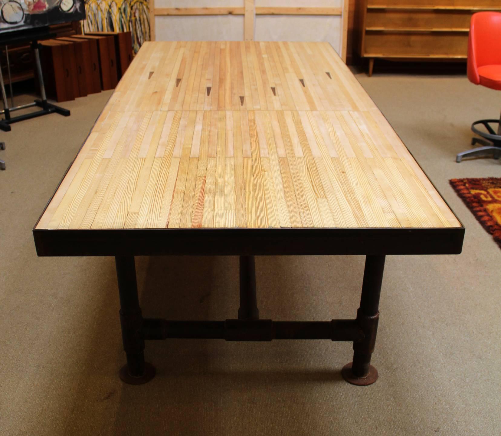 Large dining room table with vintage bowling alley floor for top and reclaimed Industrial piping for legs.