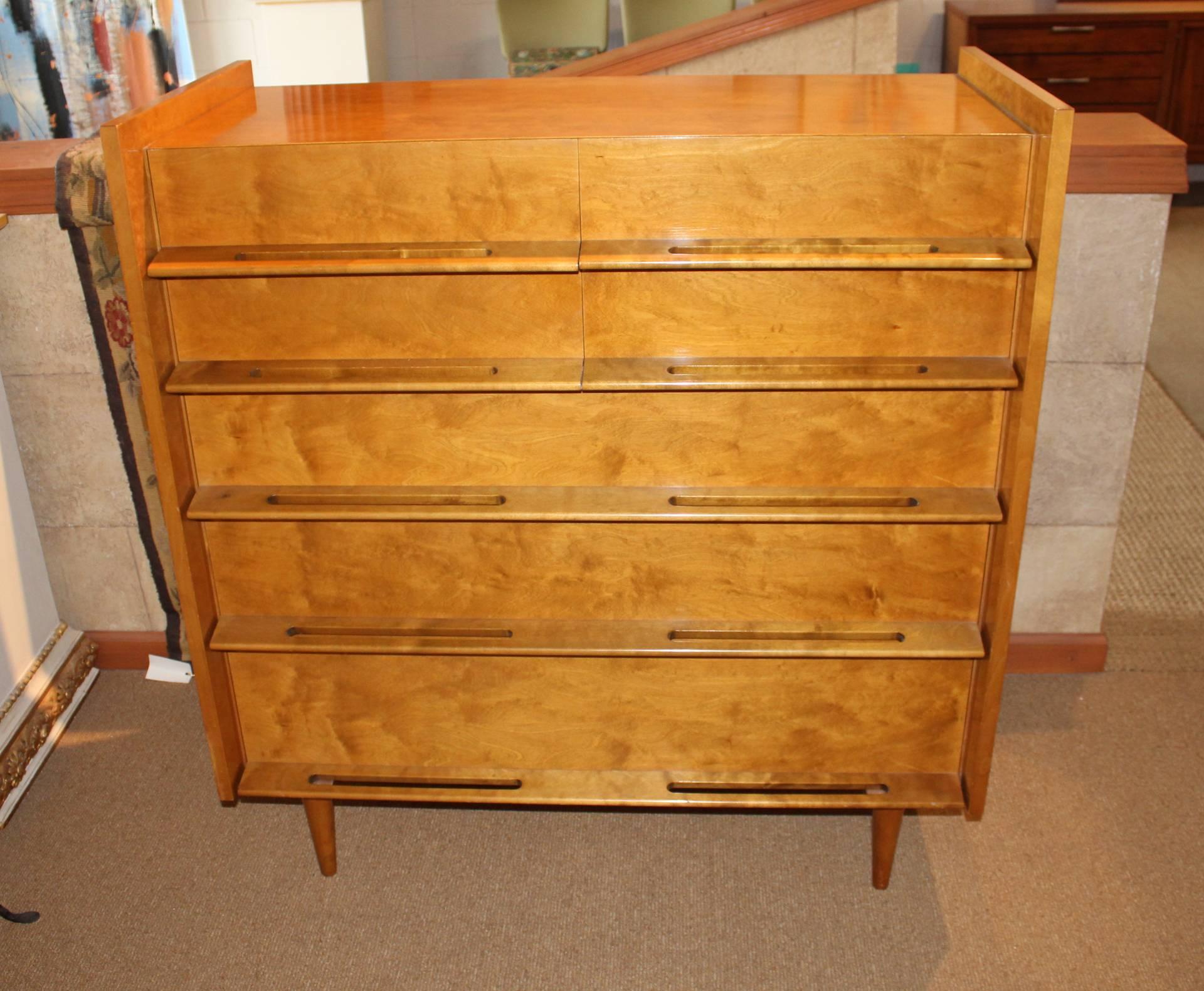 A seven-drawer chest of drawers from Edmond Spence's Coronation Collection for the Walpole Furniture Company from 1953. 

The implied volume of the bureau with its set back drawer faces, extended sideboards, tapered legs, sculpted pulls and raised