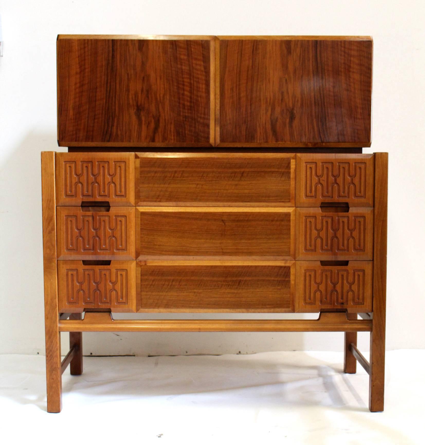 Modernist, two-piece cabinet by Swedish designer Edmund J. Spence. Two doors over three drawers. Decorative relief panels to drawer fronts. Raised on stretcher base. Marked “Made in Sweden”.