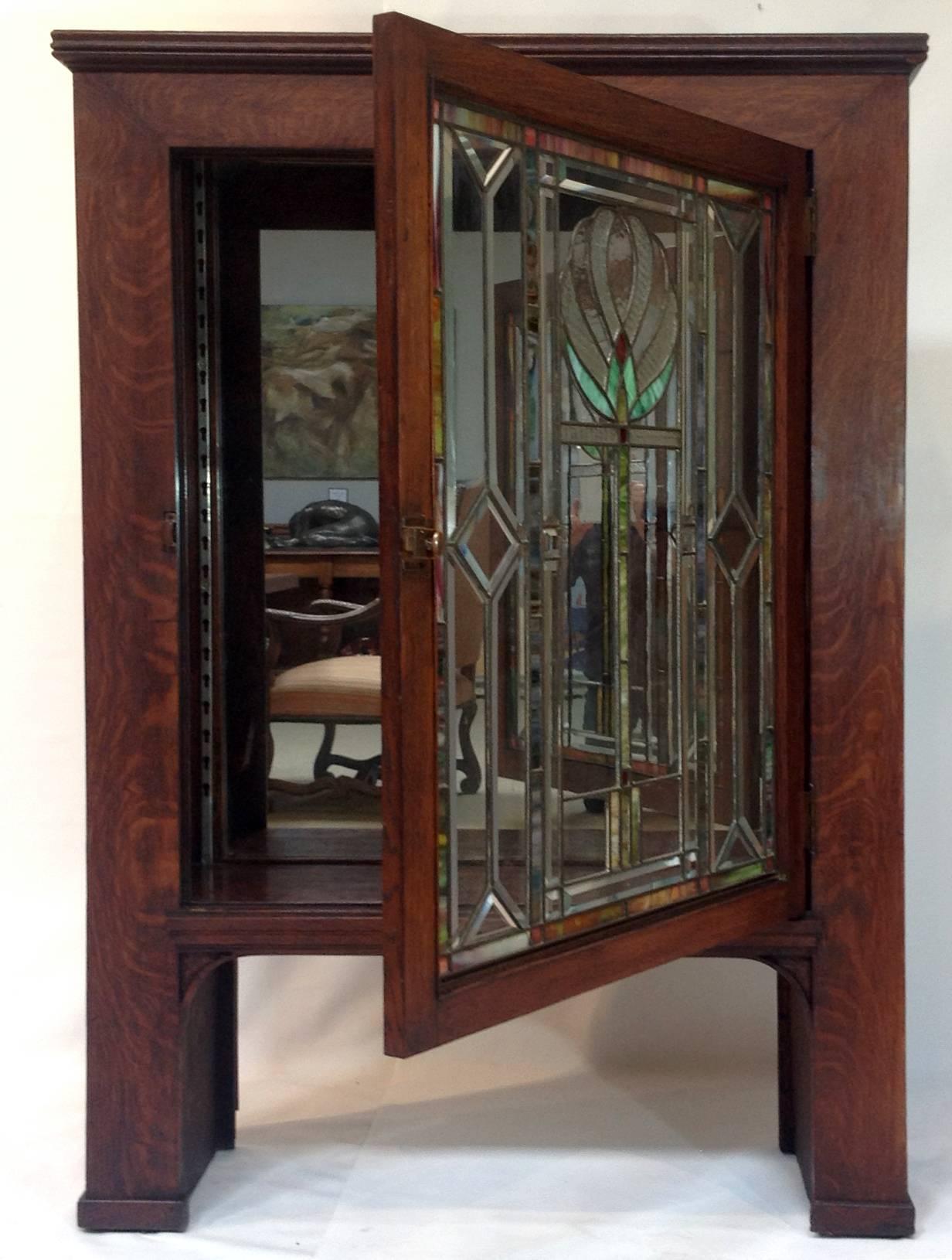Large, antique quarter-sawn oak cabinet with a beautiful stained glass door. Classic style and proportions. Mirror inside added at later time. Is set up to accept shelving.