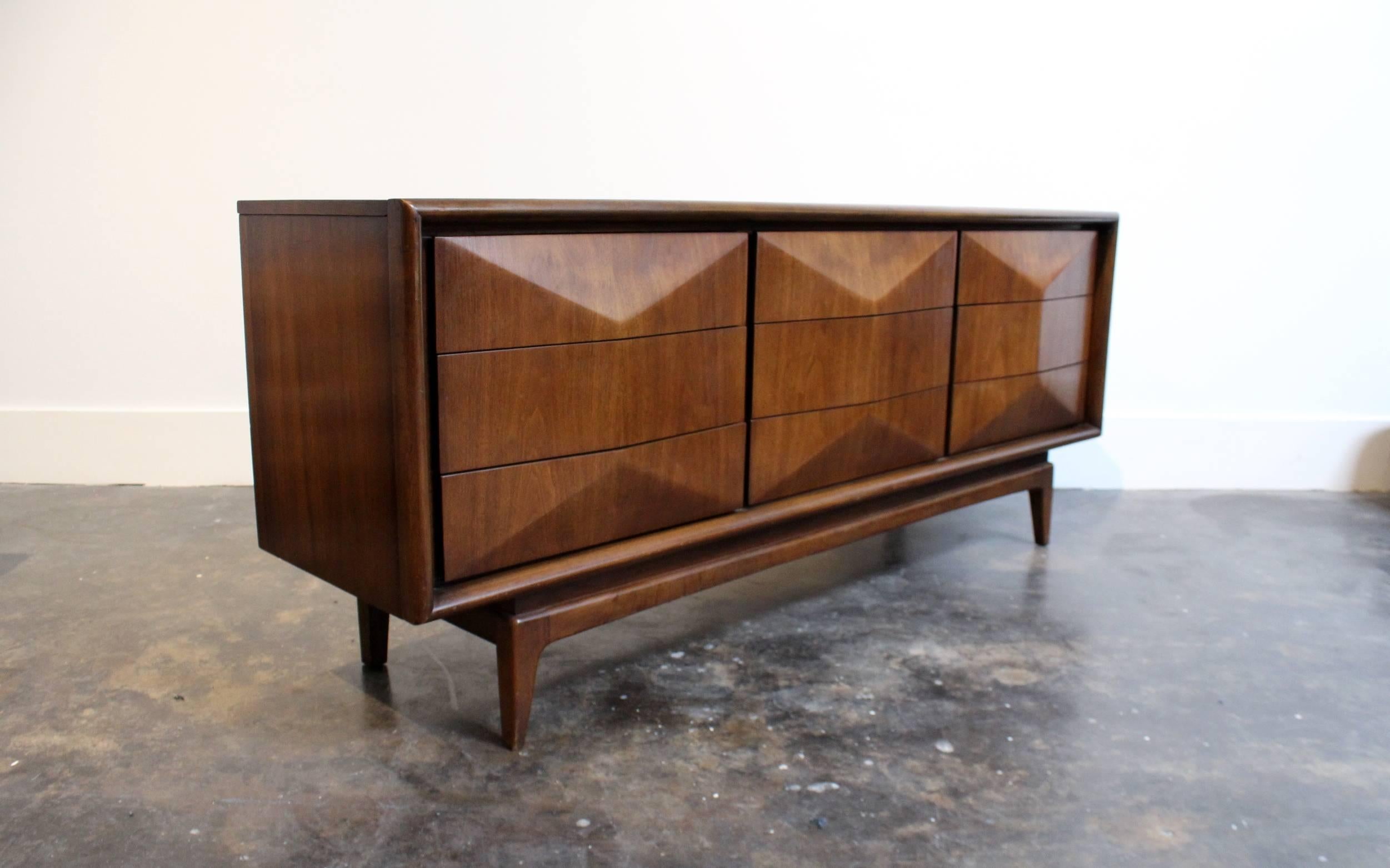 One of the most iconic designs of the era! Beautiful beveled, diamond-shaped front with 9 large drawers, glowing walnut wood, tapered feet. Has a long sleek profile with a hint of brutalist design. Good condition: light wear with small burn stain on