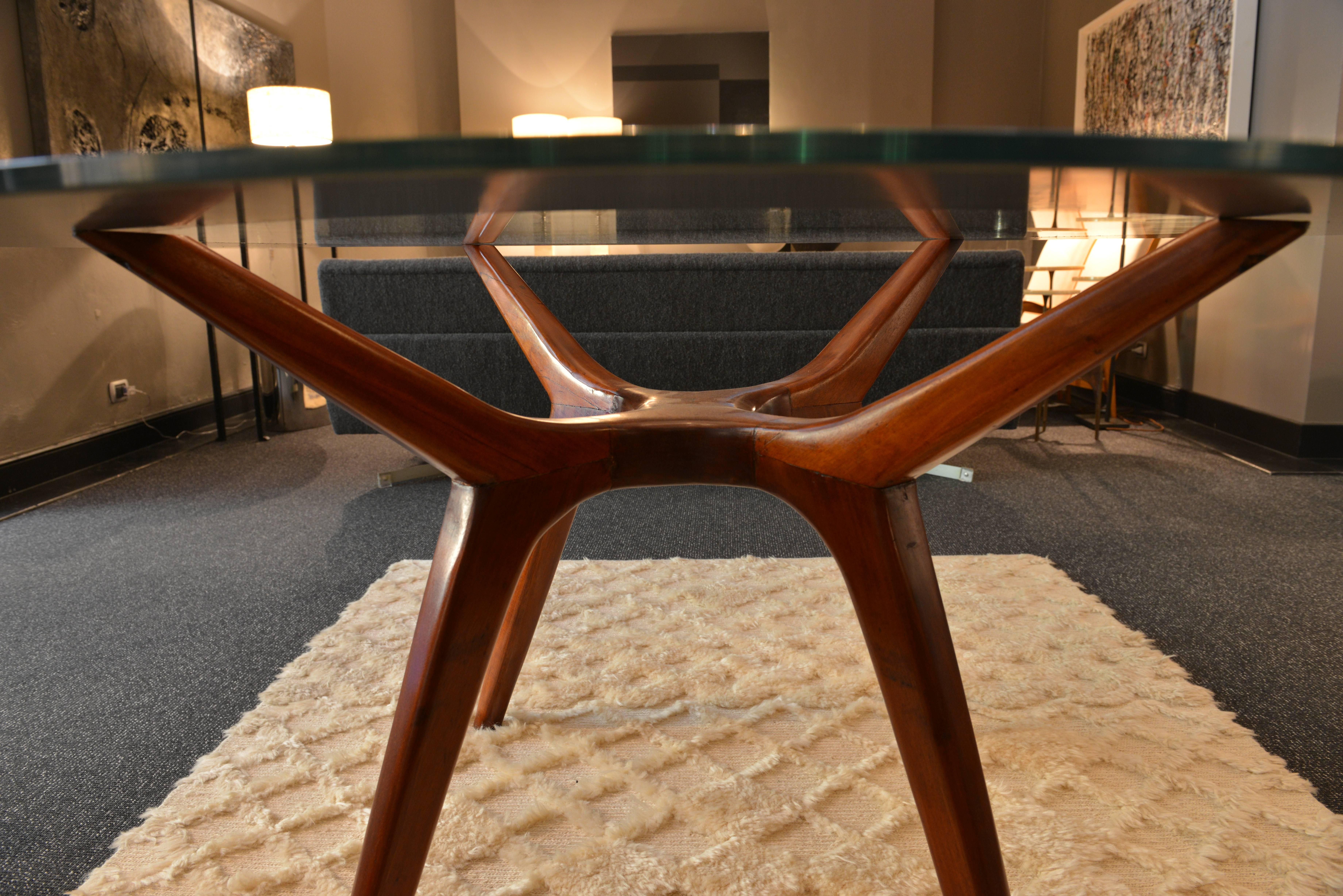 Round table realized in the United States in the early 1950s. The base is of massive natural colour walnut wood, while the clear glass top has a mirrored frame, that allows to see the details of the wooden structure.