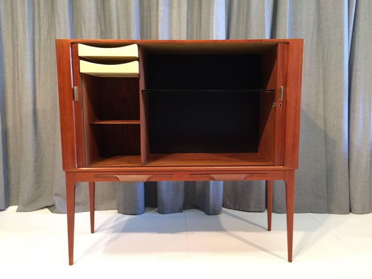 Great teak cabinet with two tambour doors, two drawers and two shelves. The cabinet has also two pull-out trays in the front. The lock and pulls are brass. Comes with one key.