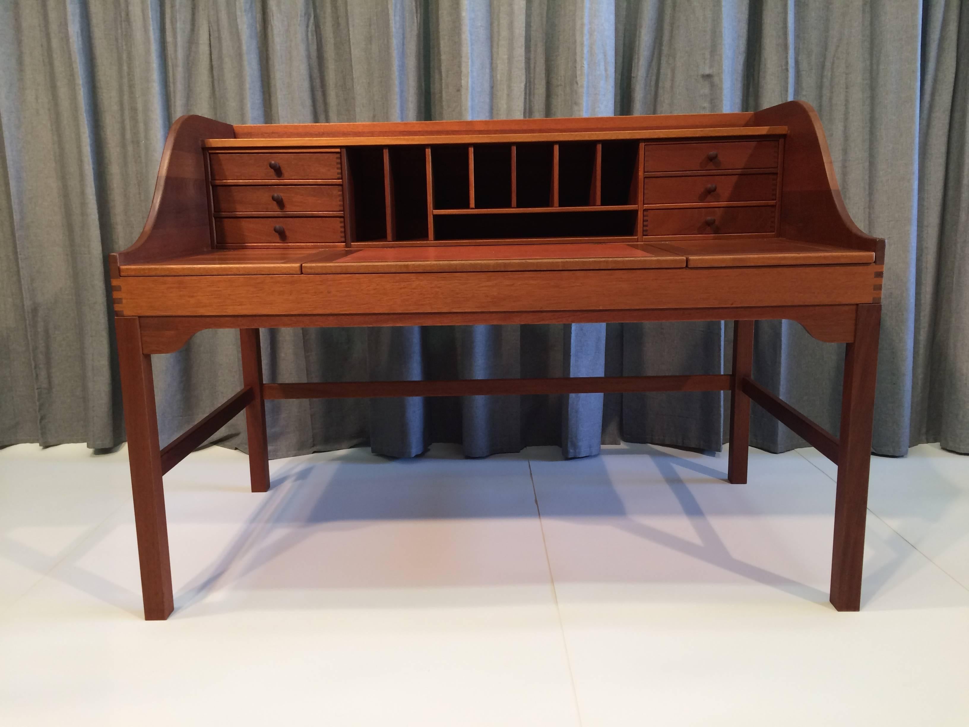 Beautiful desk made of solid mahogany, leather and brass hardware. the craftsmanship is stunning. the desk has plenty of storage under writing surface and has six drawers. Made in Denmark.