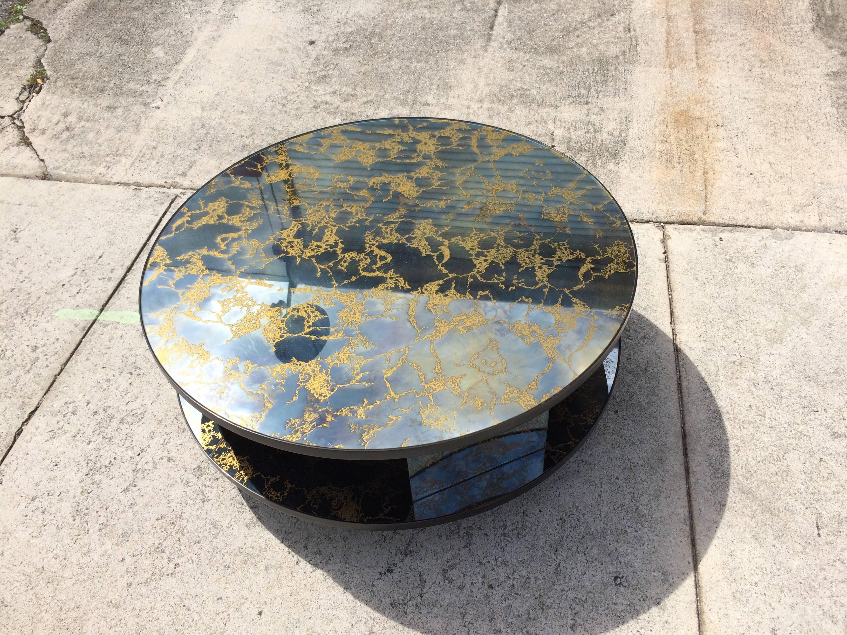 Two-tier rotating coffee table with smoked mirror and gold vein details and black painted wood.