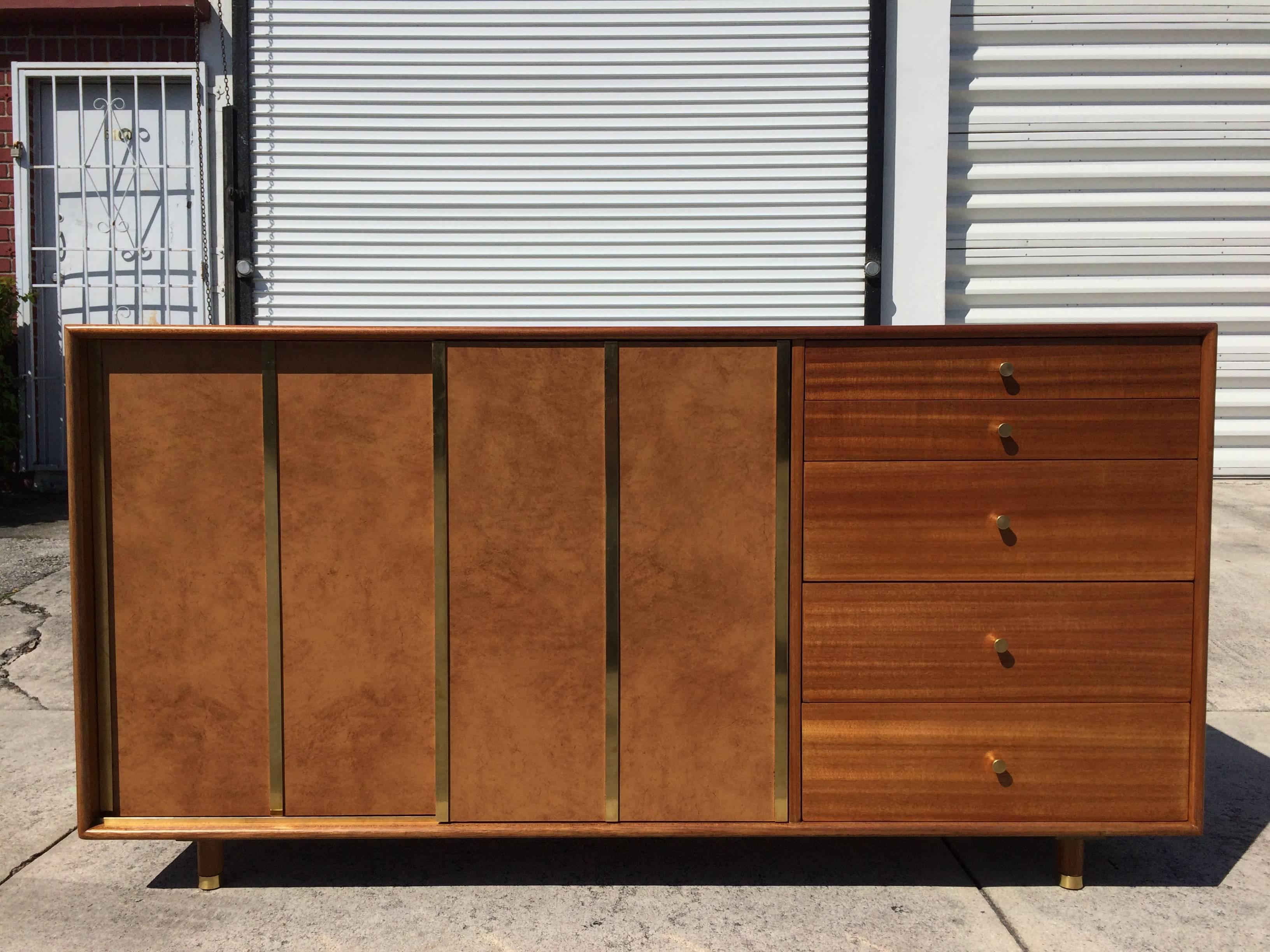 Credenza standing on five legs, five drawers and two sliding doors. Behind the sliding doors are four white drawers and three shelves.